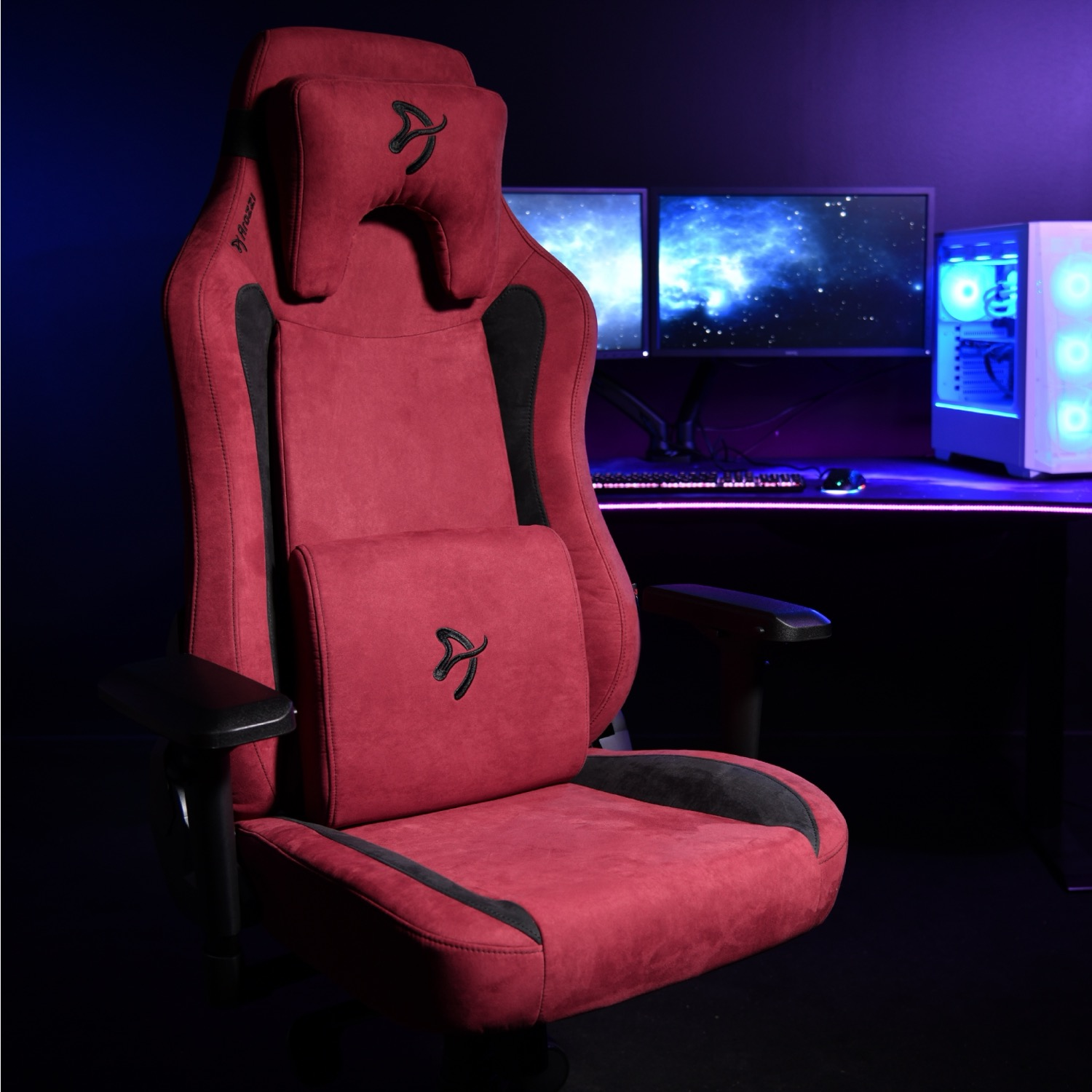 Een rode gamestoel met zwarte accenten en hoofdsteun staat voor een bureau.