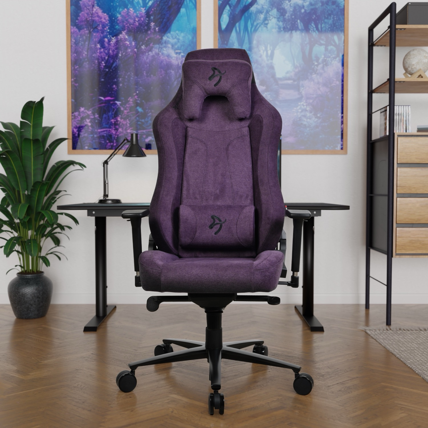 Una sedia da gaming viola si trova di fronte a una scrivania con stampe d'arte.