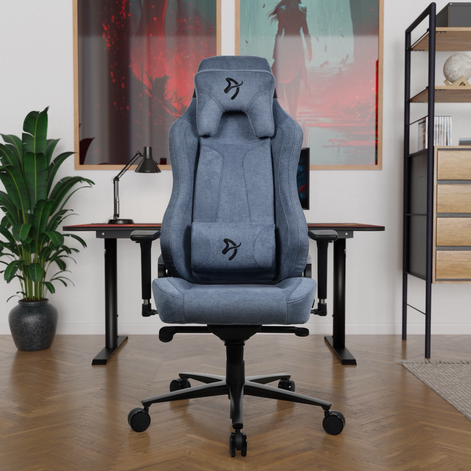 Een blauwe gamestoel voor een bureau met twee kunstwerken aan de muur.