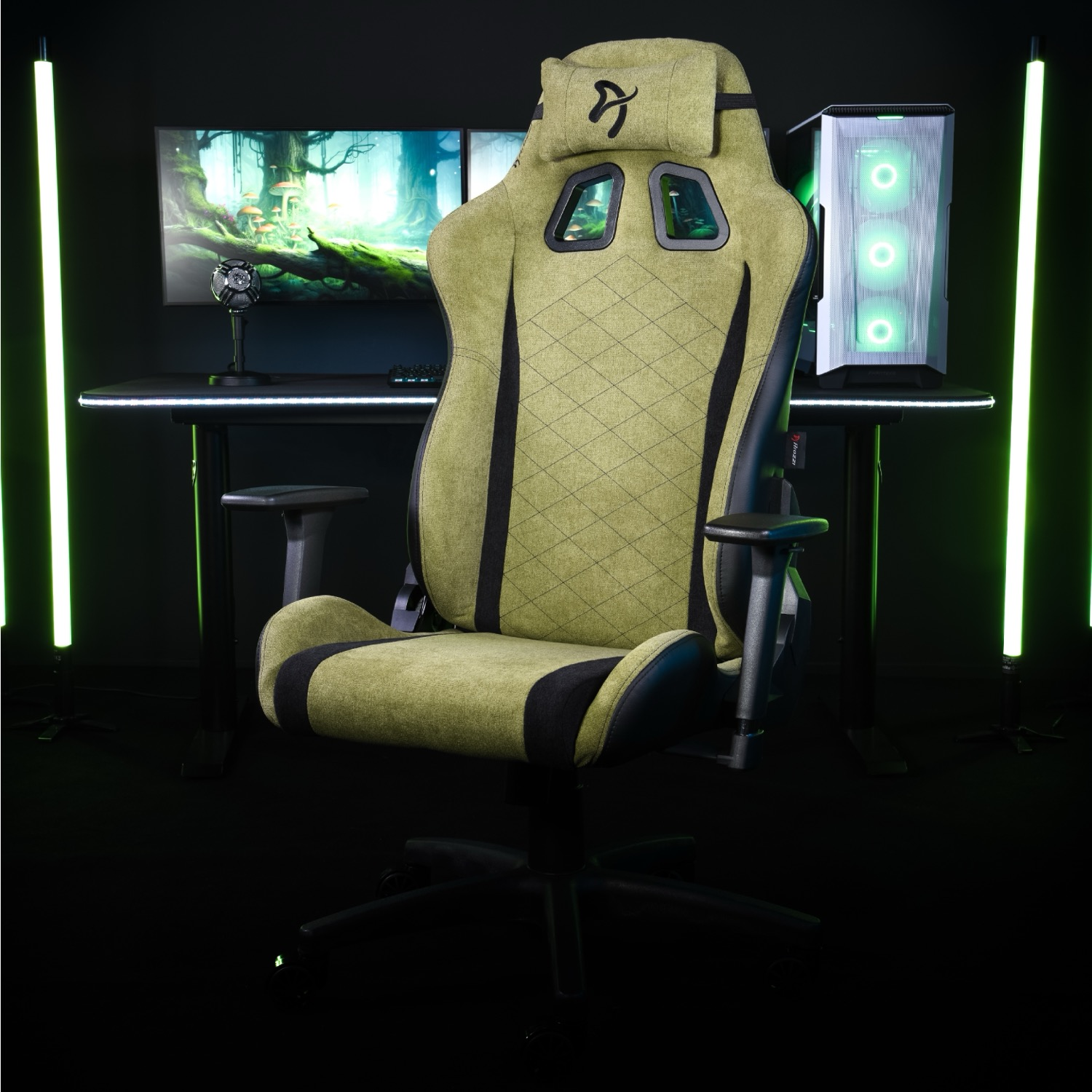 Een groene gamestoel staat voor een bureau met computers en monitoren, verlicht door groene lampen.