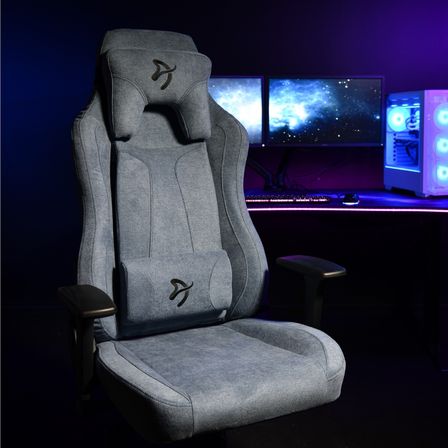 Een grijze gamestoel met hoofd- en lendekussens voor computermonitoren.
