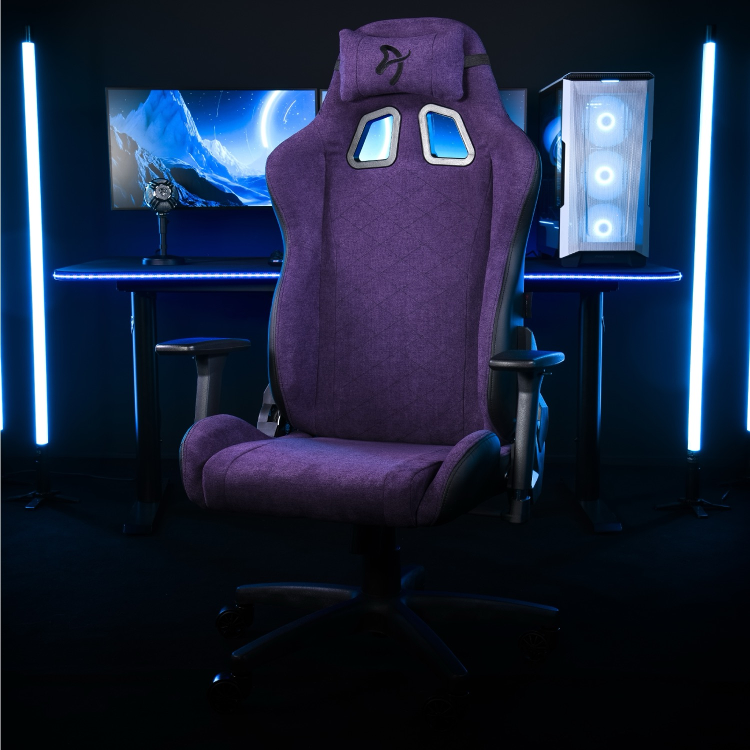Een paarse gamestoel staat voor een bureau met monitor en pc.