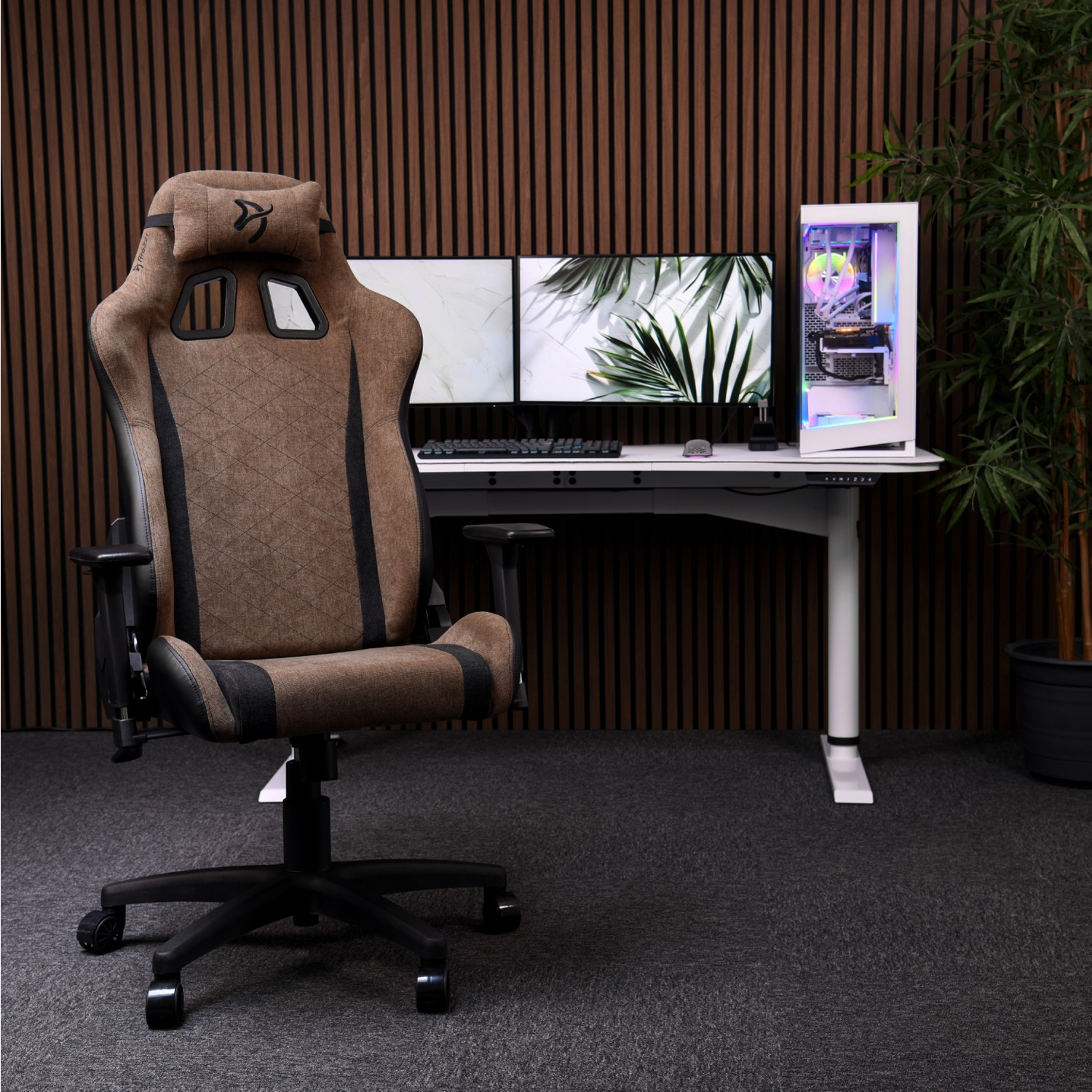 Een bruine gamestoel voor een bureau met pc's en monitoren.