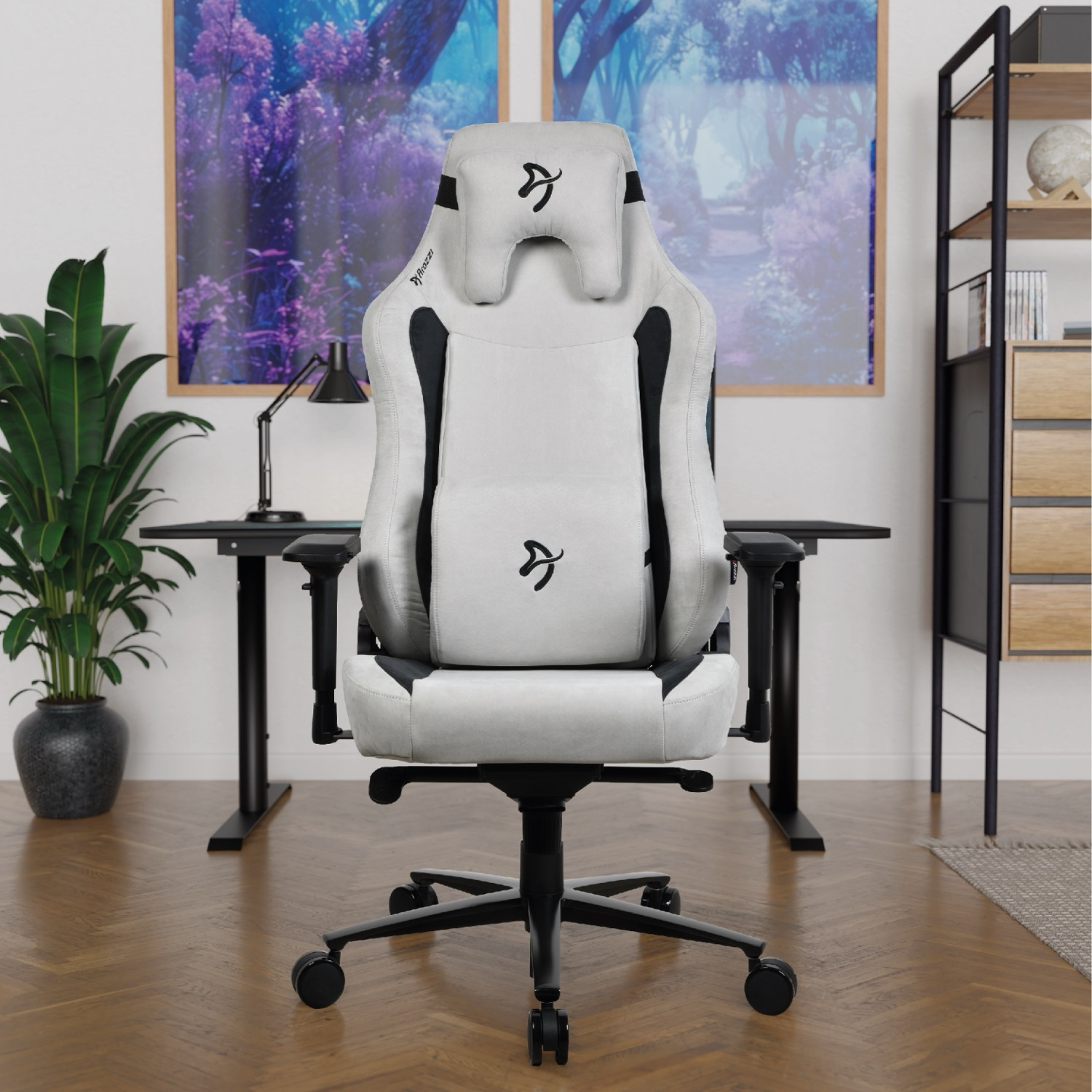 Ein weißer Gaming-Stuhl mit schwarzem Akzent vor einem Schreibtisch mit zwei Bildern.