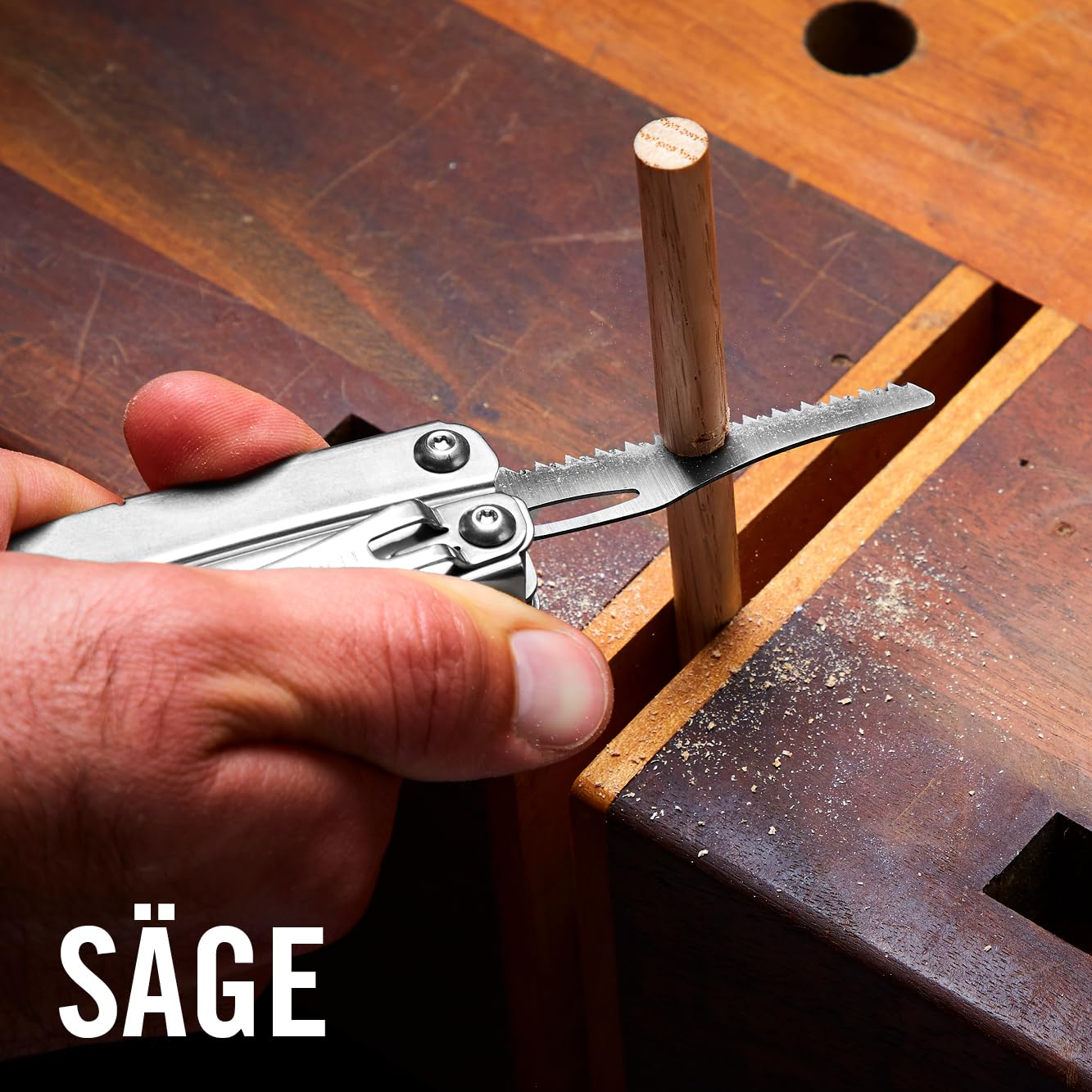 Una mano usa una sega multiuso per tagliare un tassello di legno.