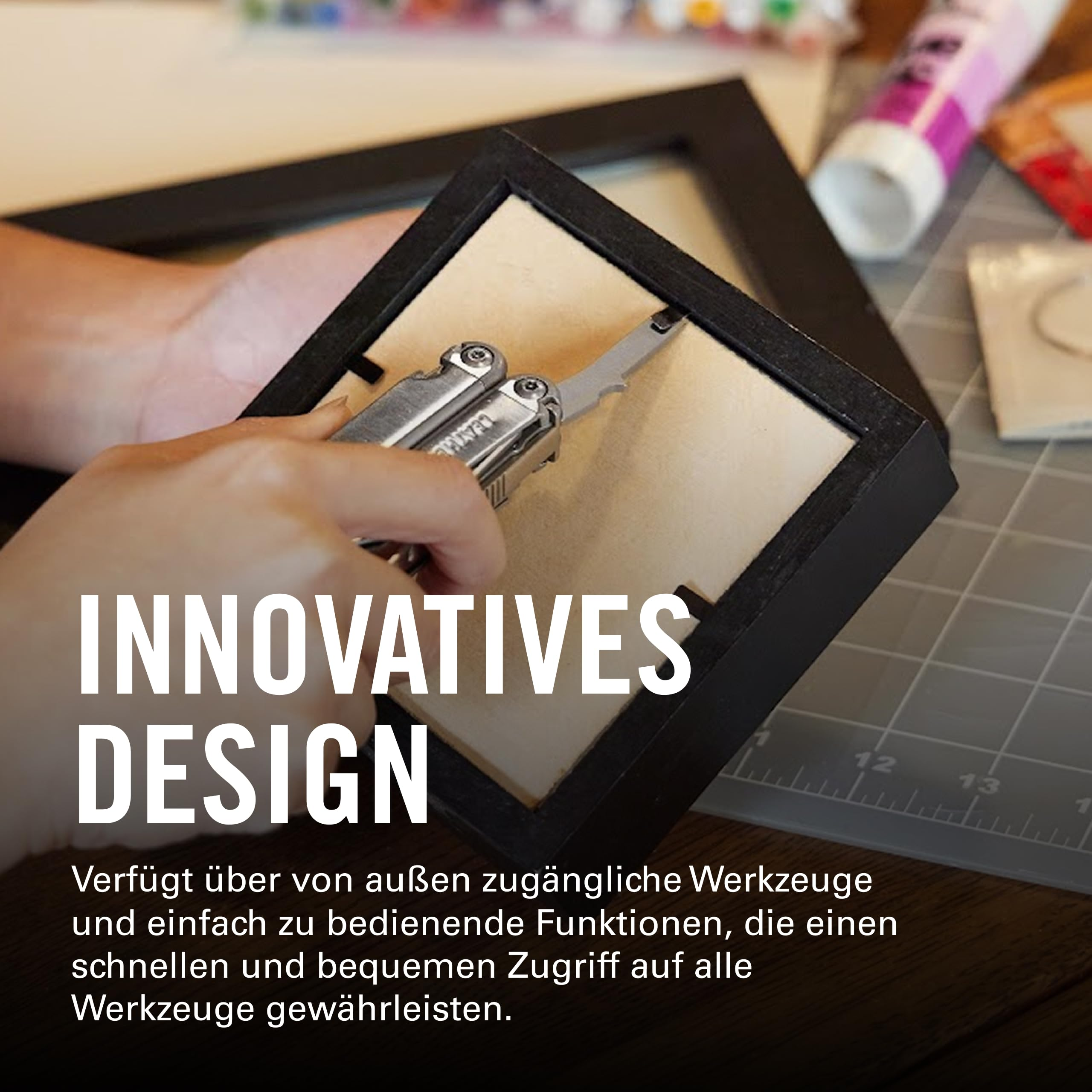 Eine Hand benutzt ein silbernes Multitool, um einen schwarzen Bilderrahmen zu öffnen.