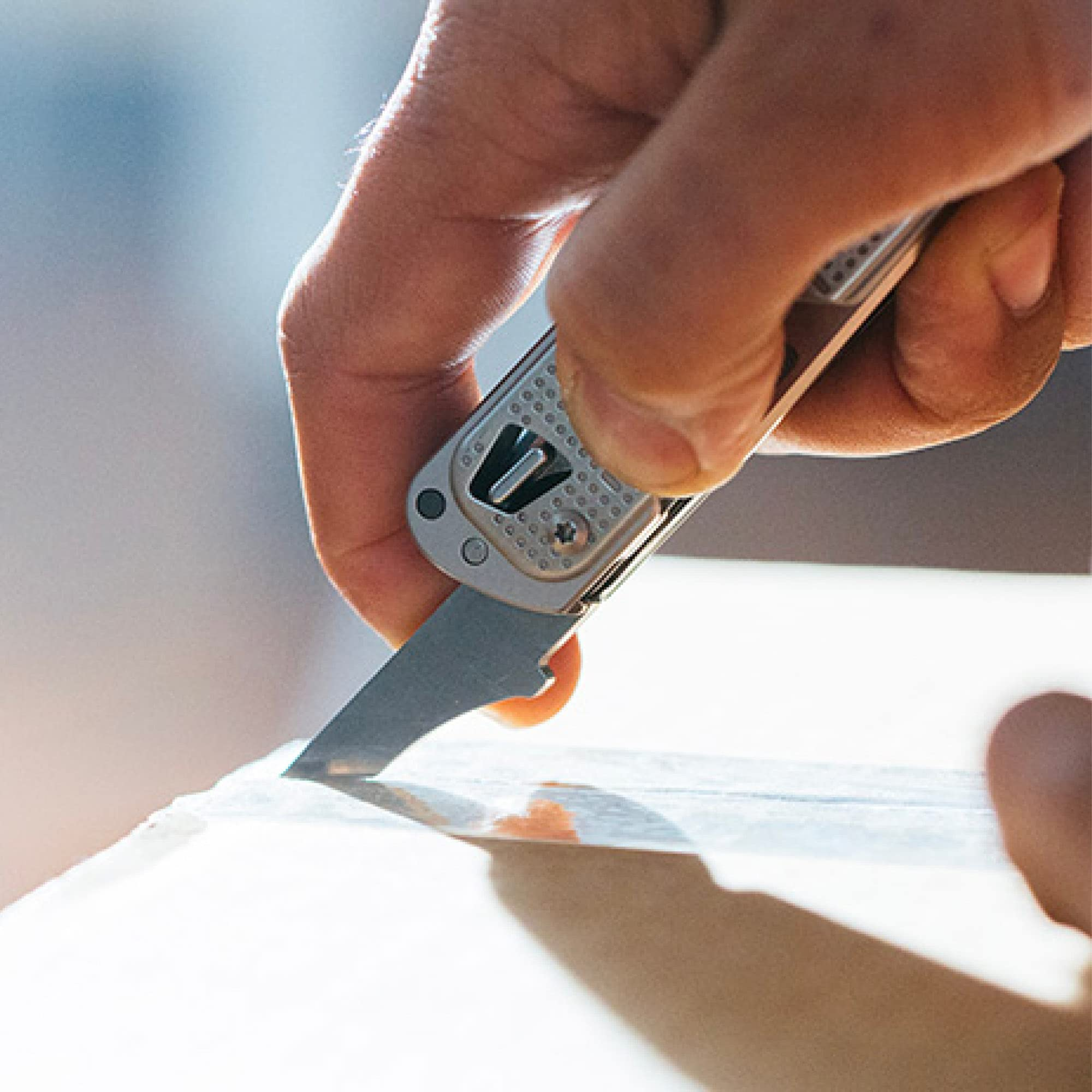 Eine Hand benutzt ein Messer, um Klebeband auf einer Kiste zu schneiden.
