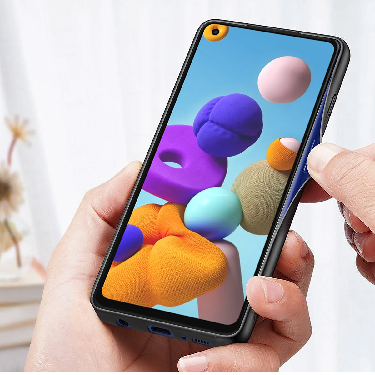 Una mano tiene uno smartphone con grafica astratta colorata. Un'altra mano fa scorrere una cover.