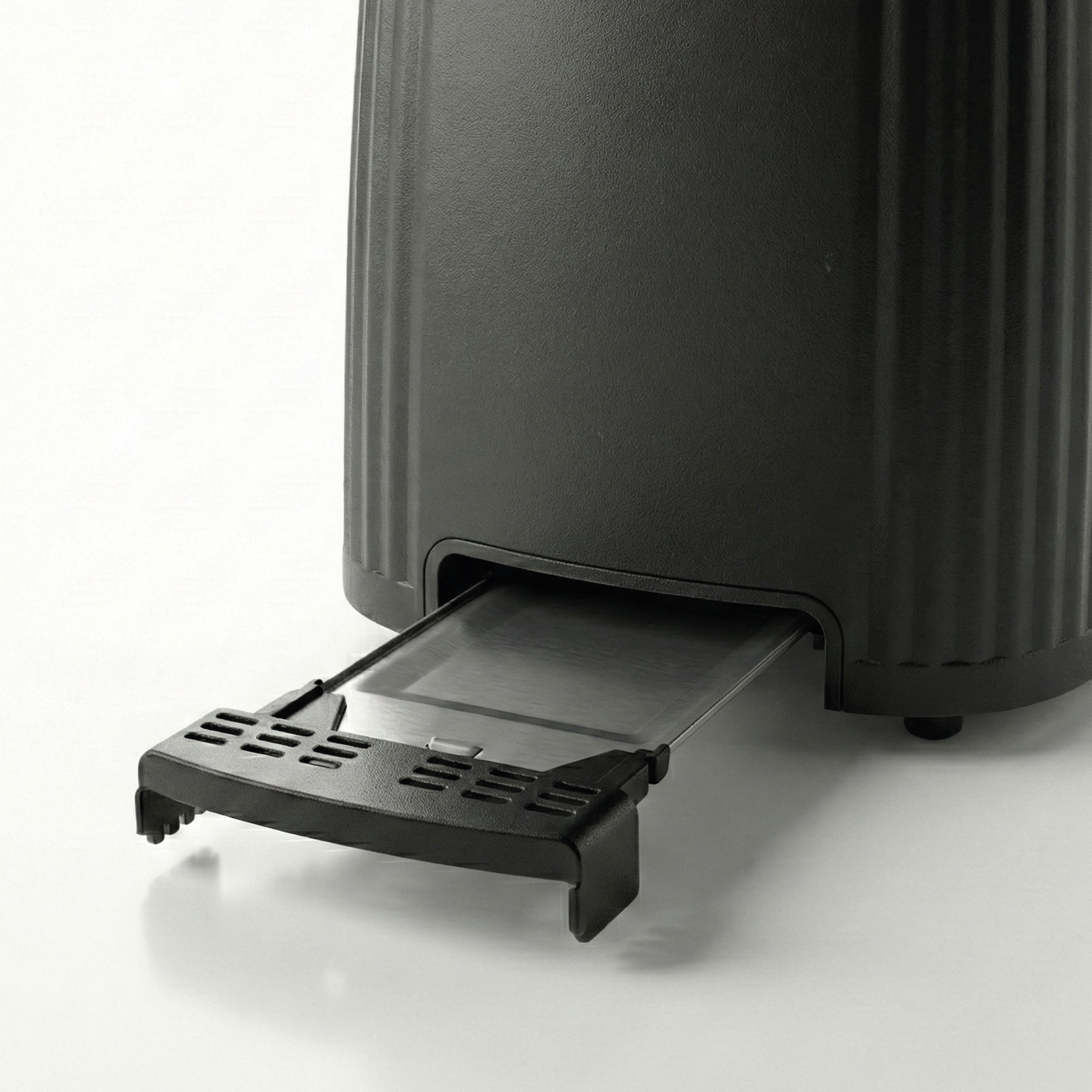 Black toaster with its crumb tray pulled out, on a white background.