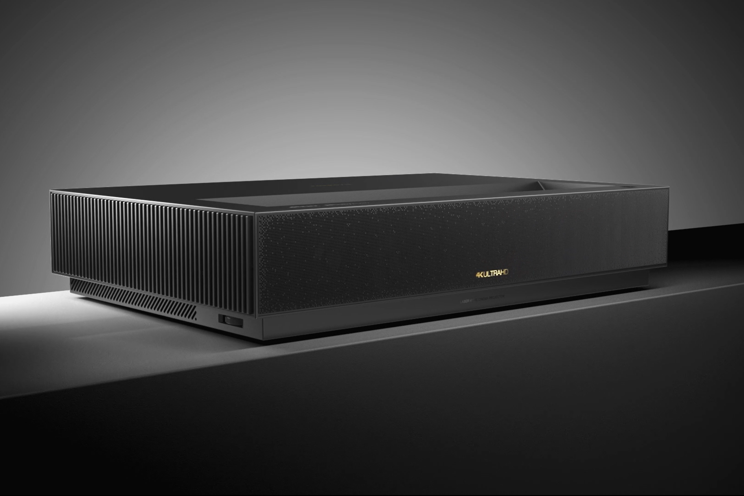 Ein schwarzer 4K Ultra HD Laser-Kinoprojektor steht auf einer dunklen Oberfläche.