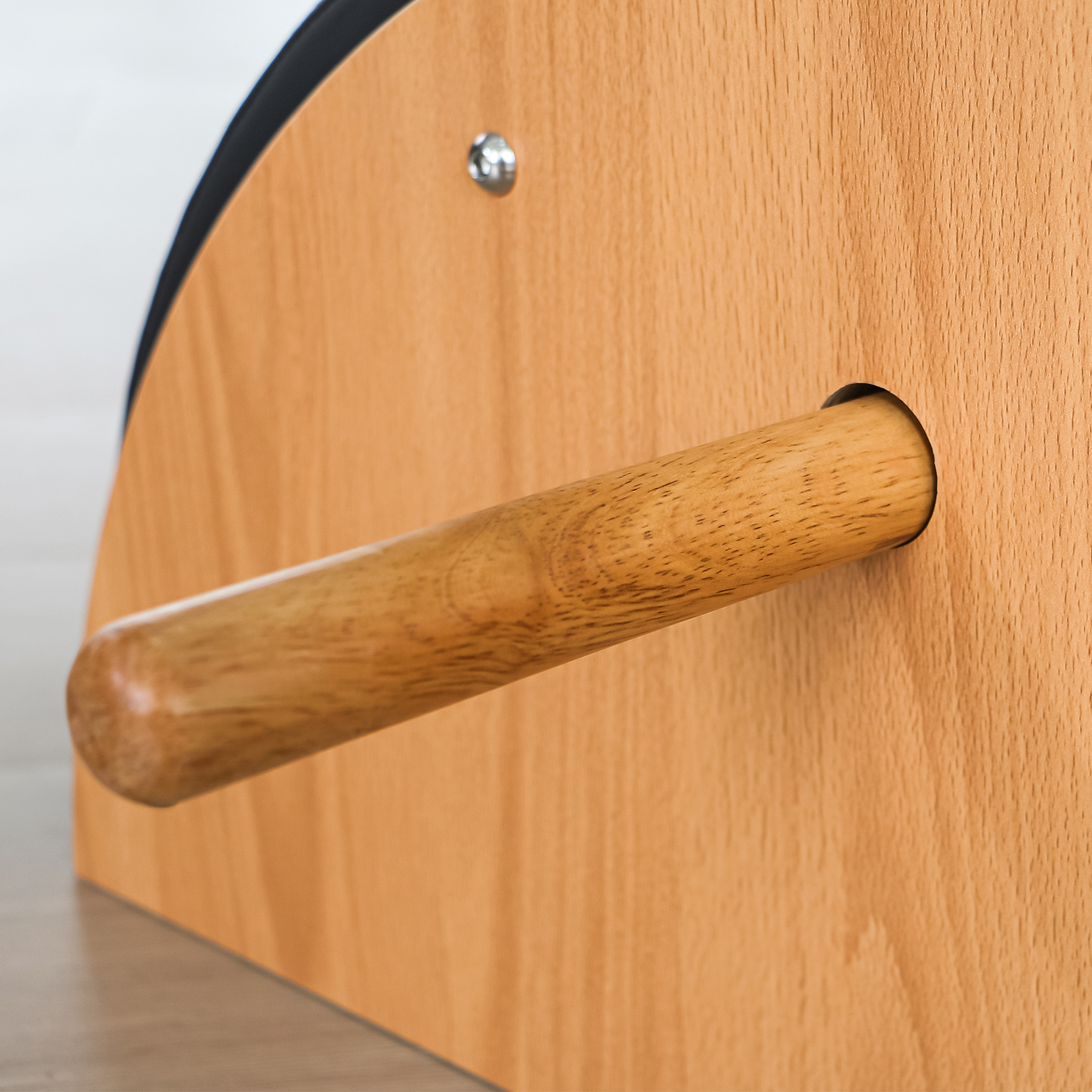 Un manico di legno sporge da un pannello di legno marrone chiaro con bordo nero.