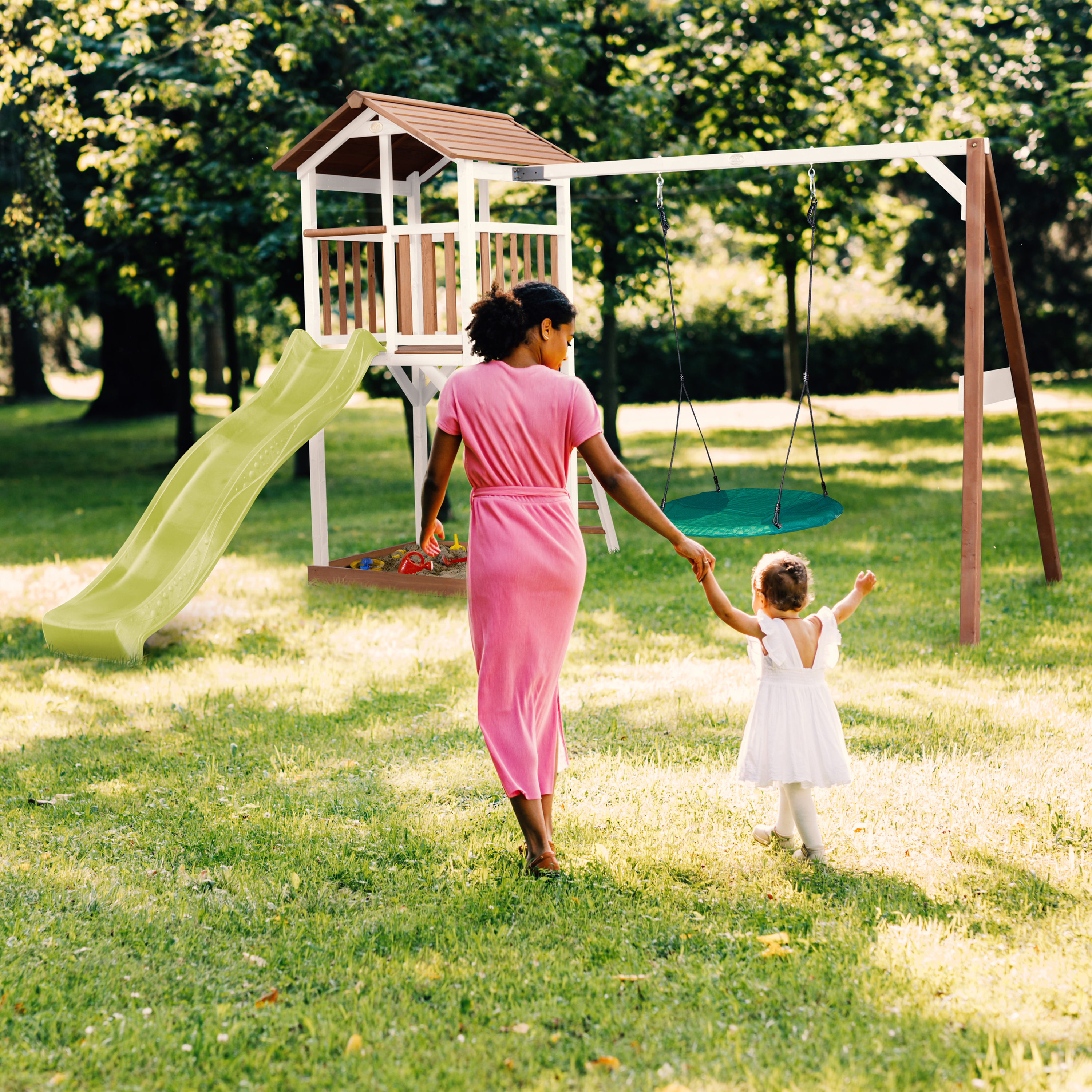 Frau und Kind gehen zum Spielplatz mit Rutsche und Schaukel.