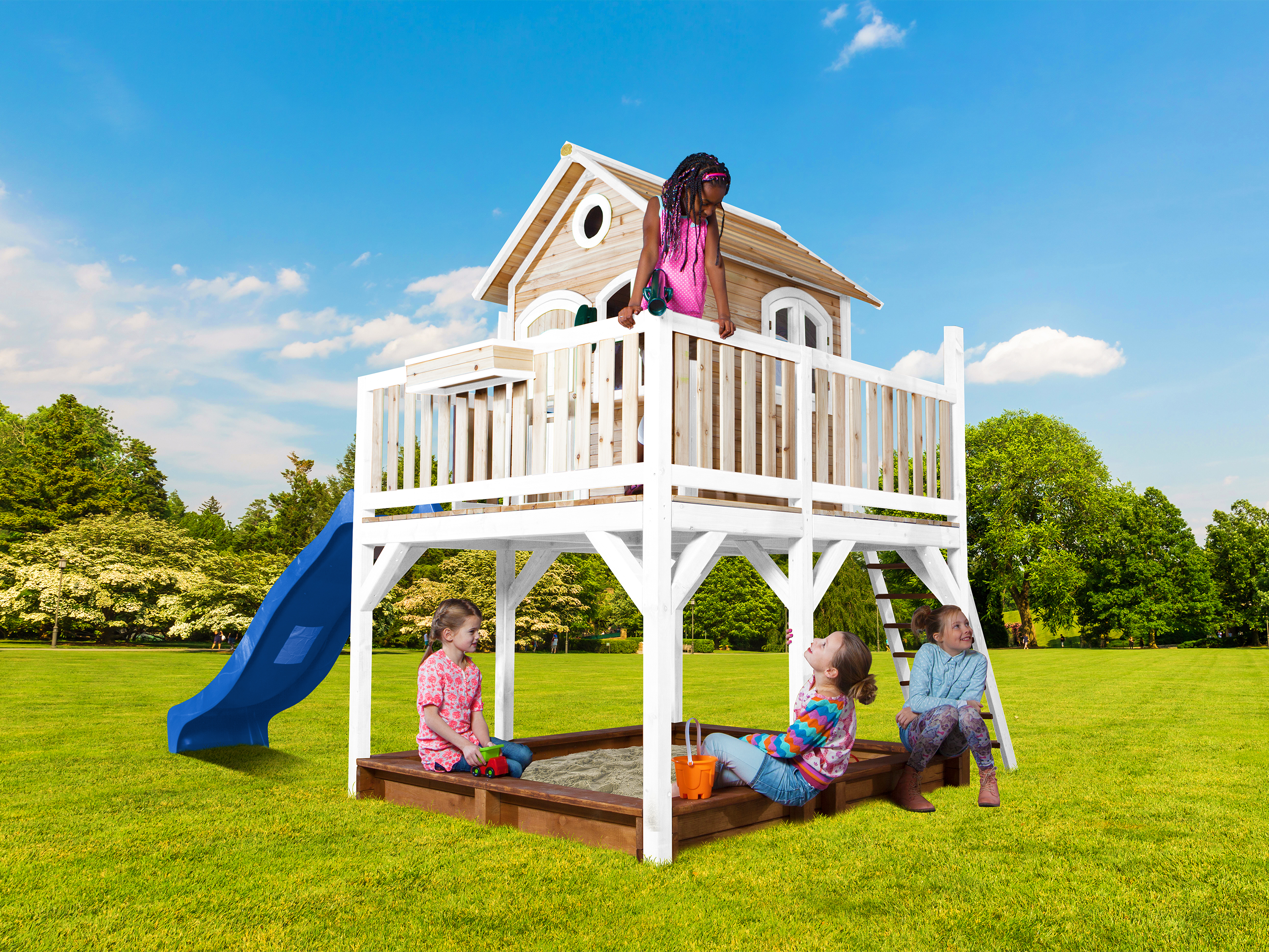 Kinder spielen auf einem Spielhaus mit Rutsche und Sandkasten im Garten.