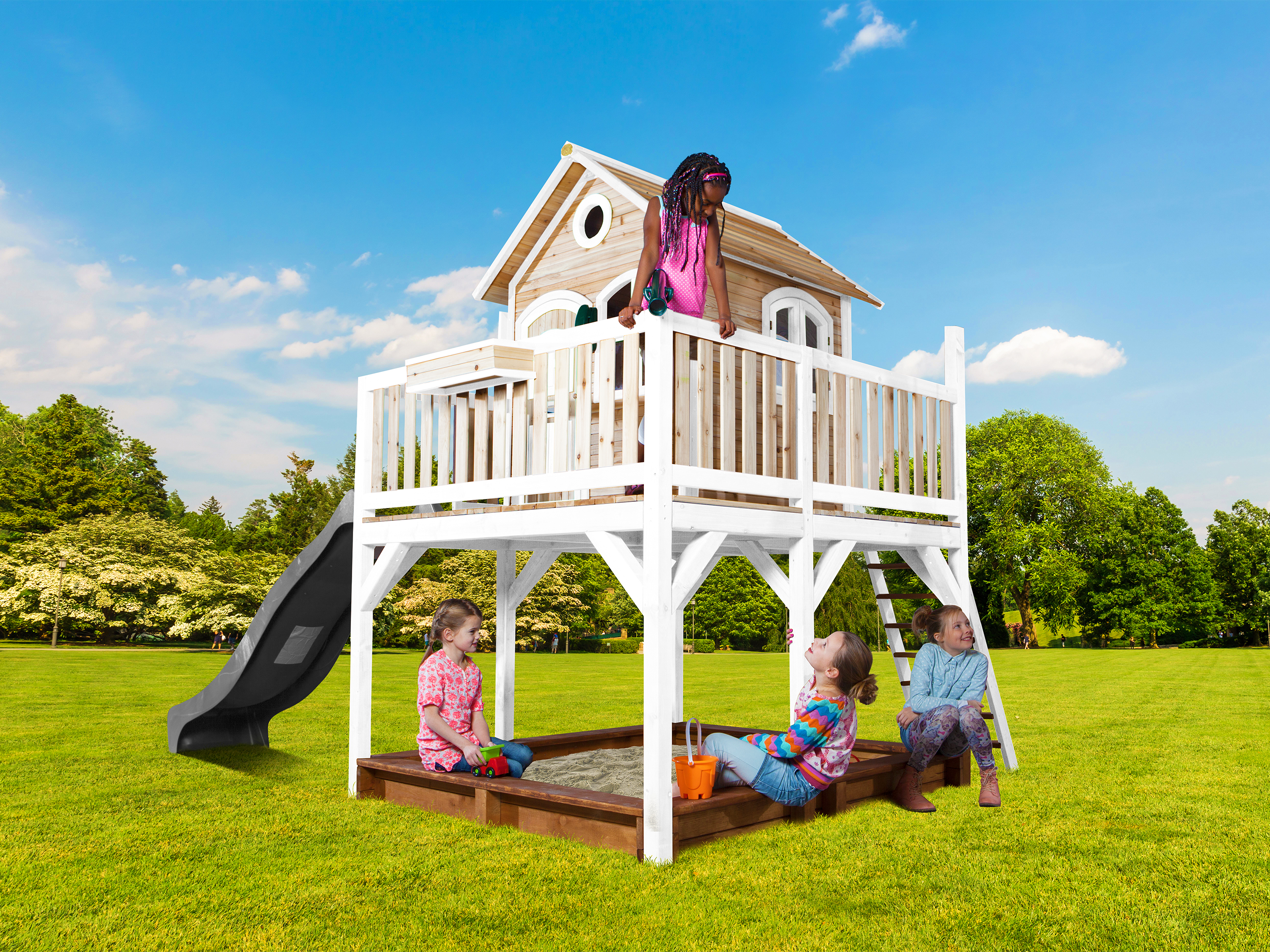 Kinder spielen auf einem Spielturm mit Rutsche und Sandkasten im Garten.