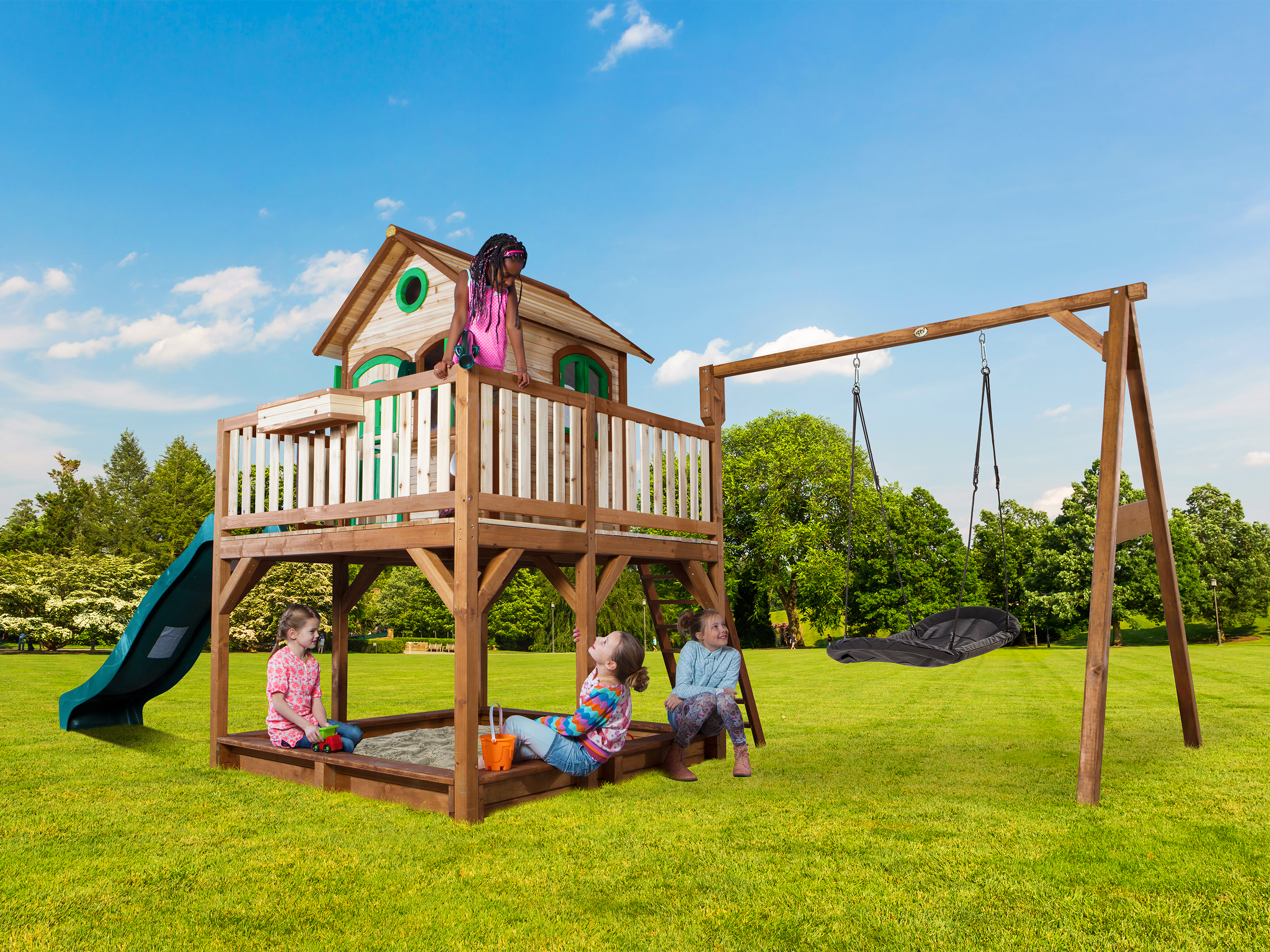 Kinder spielen auf einem Holzspielturm mit Rutsche und Schaukel im Garten.