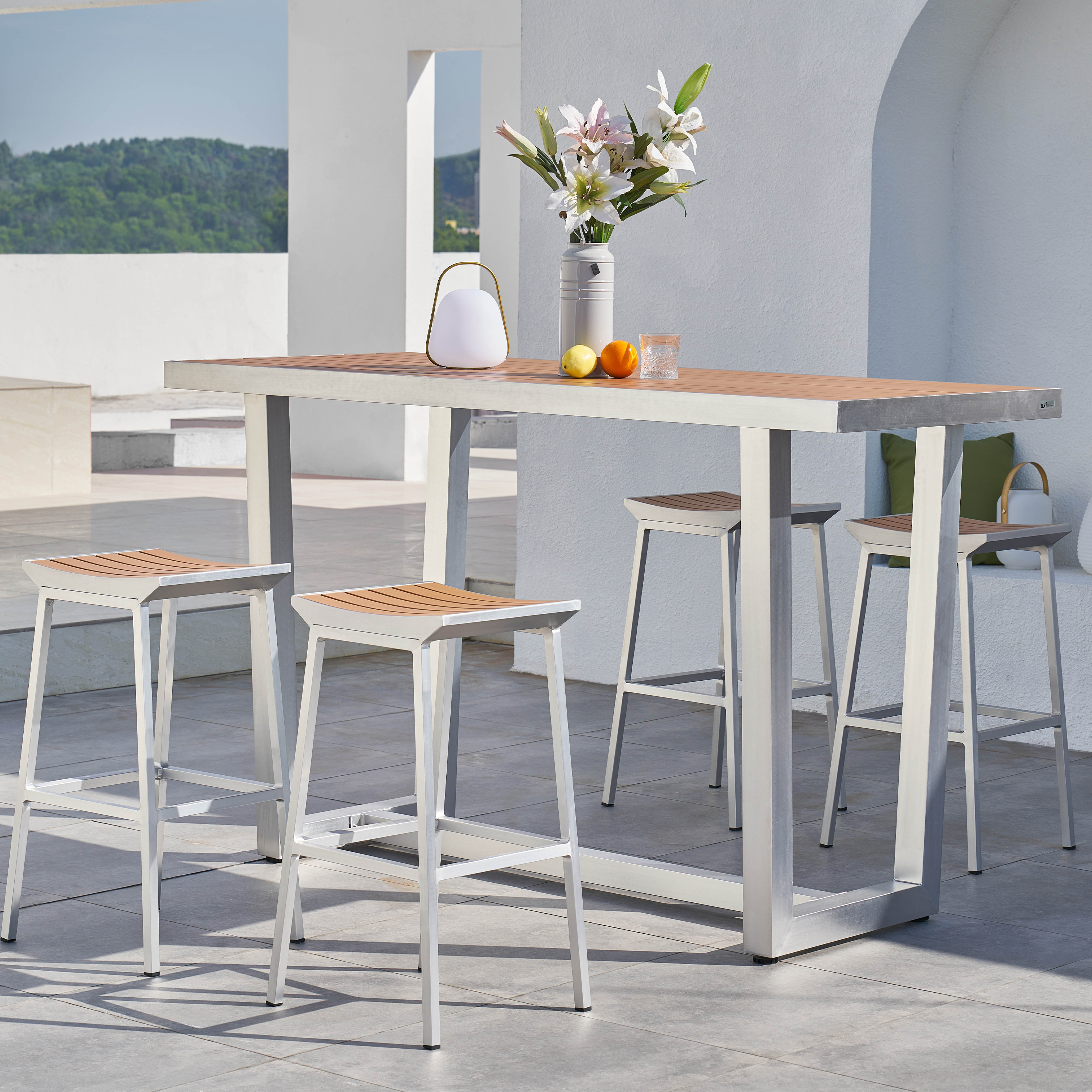 Ein rechteckiger Tisch mit vier Barhockern im Freien, dekoriert mit Blumen und Früchten.