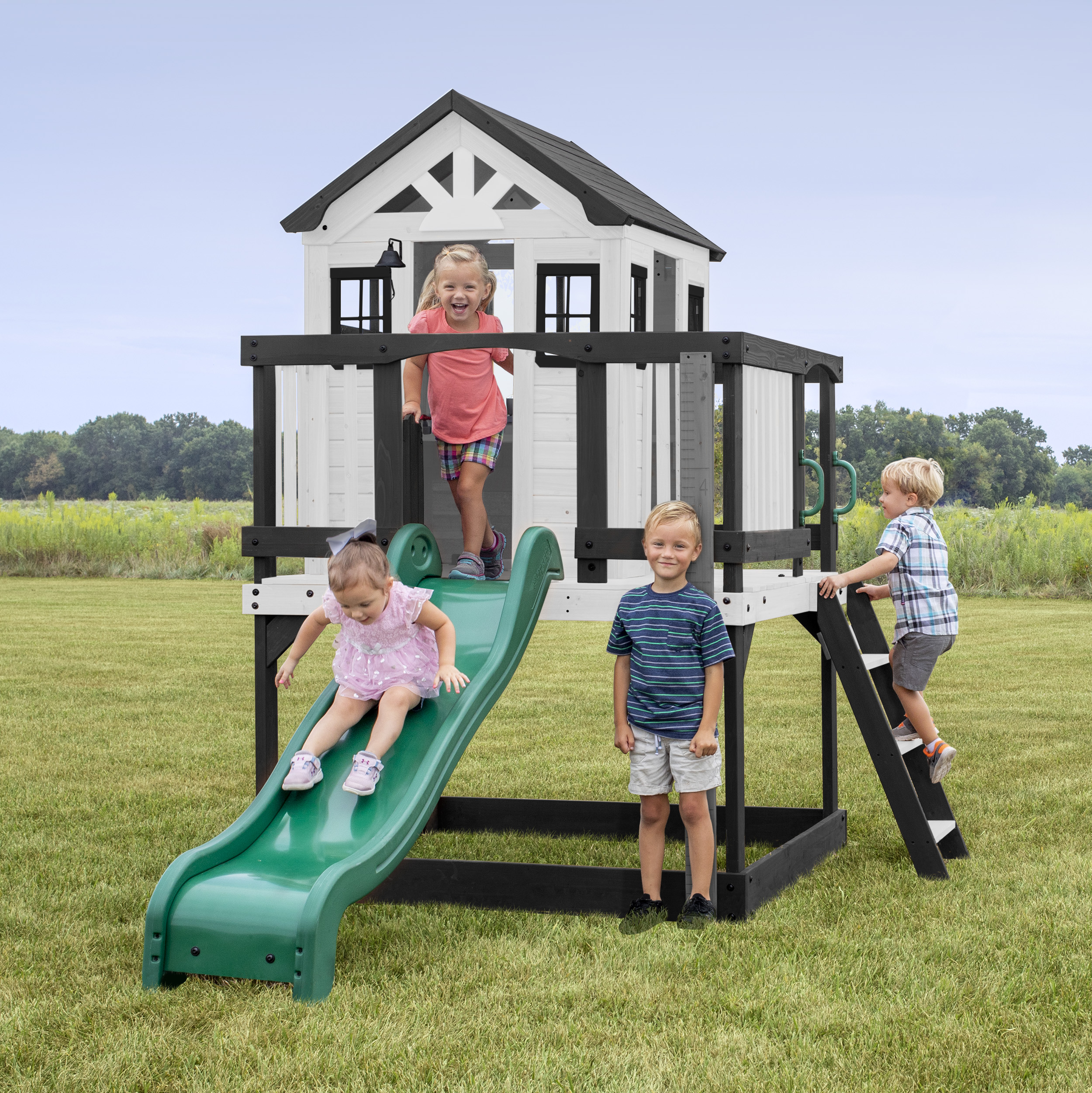 Kinder spielen auf einem Spielturm mit Rutsche und Leiter im Garten.
