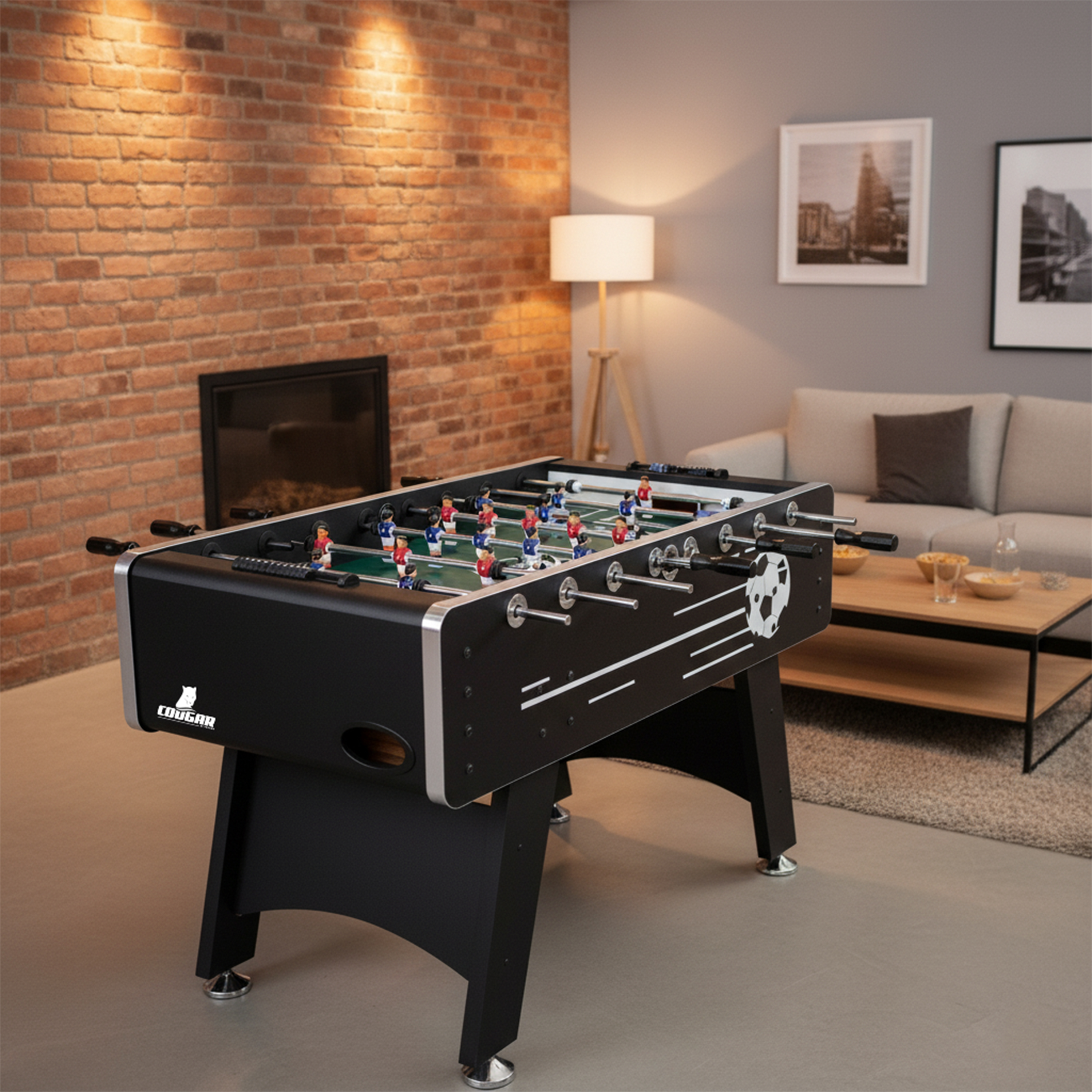 Ein schwarzer Tischfußballtisch mit roten und blauen Spielern steht in einem Wohnzimmer.