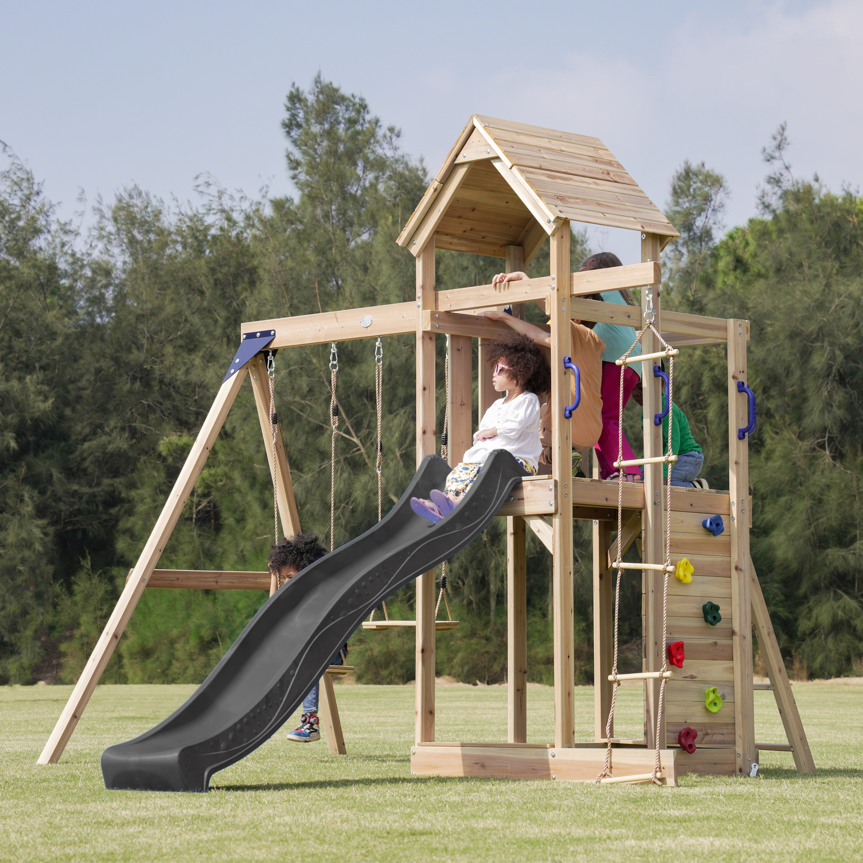 Kinder spielen auf einem Holzspielturm mit Rutsche und Schaukeln im Freien.