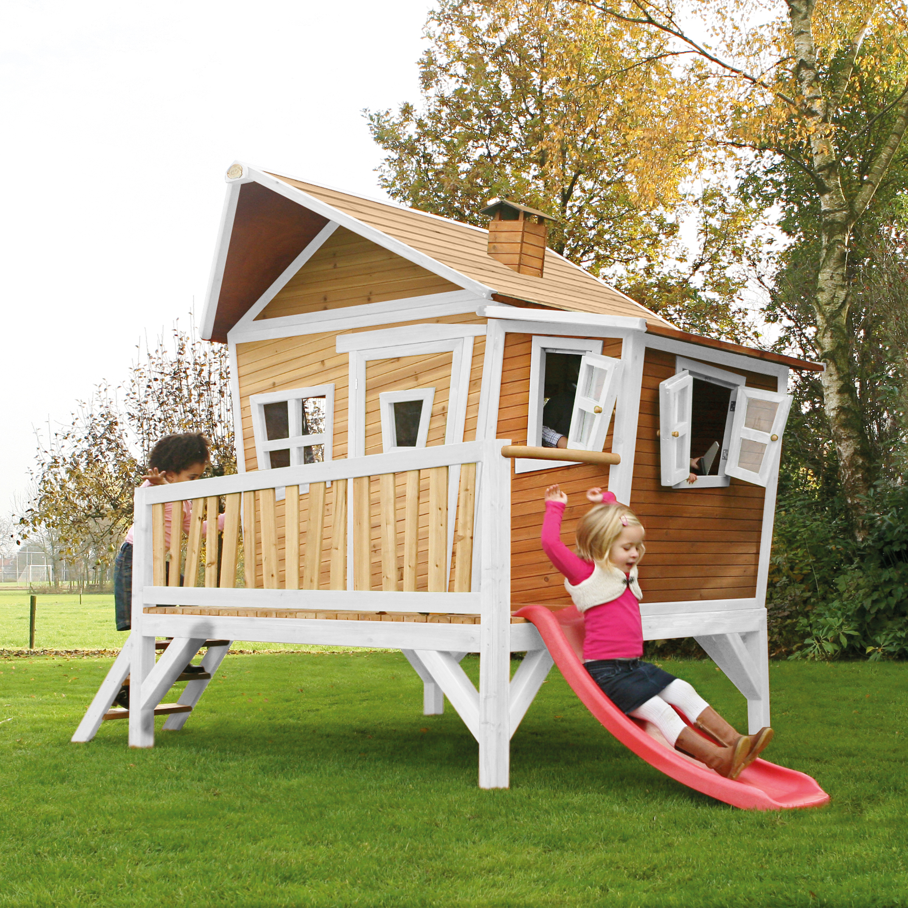 Kinder spielen auf einem Baumhaus mit Rutsche im Garten.