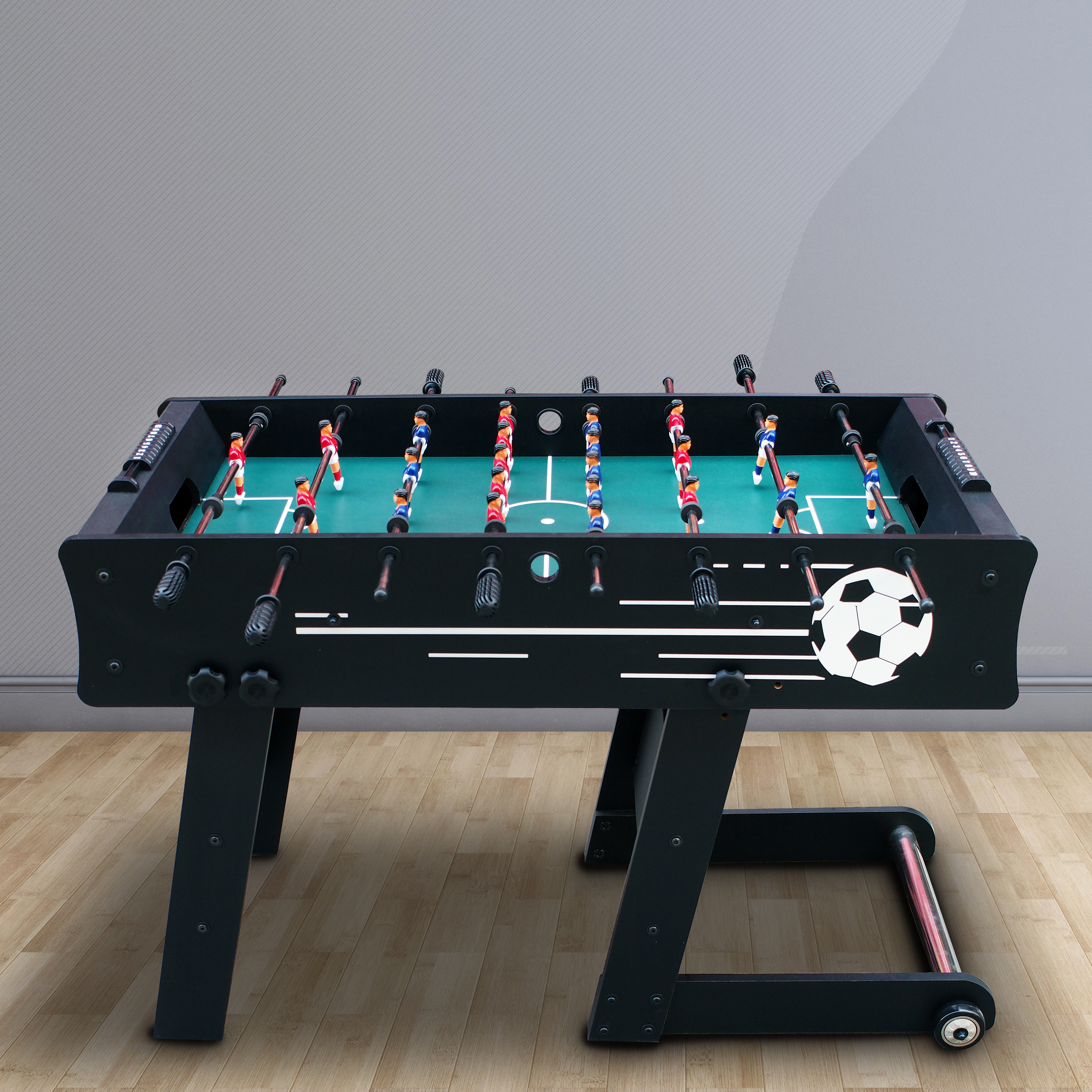 Ein schwarzer Tischfußballtisch mit roten und blauen Spielern auf grünem Feld.