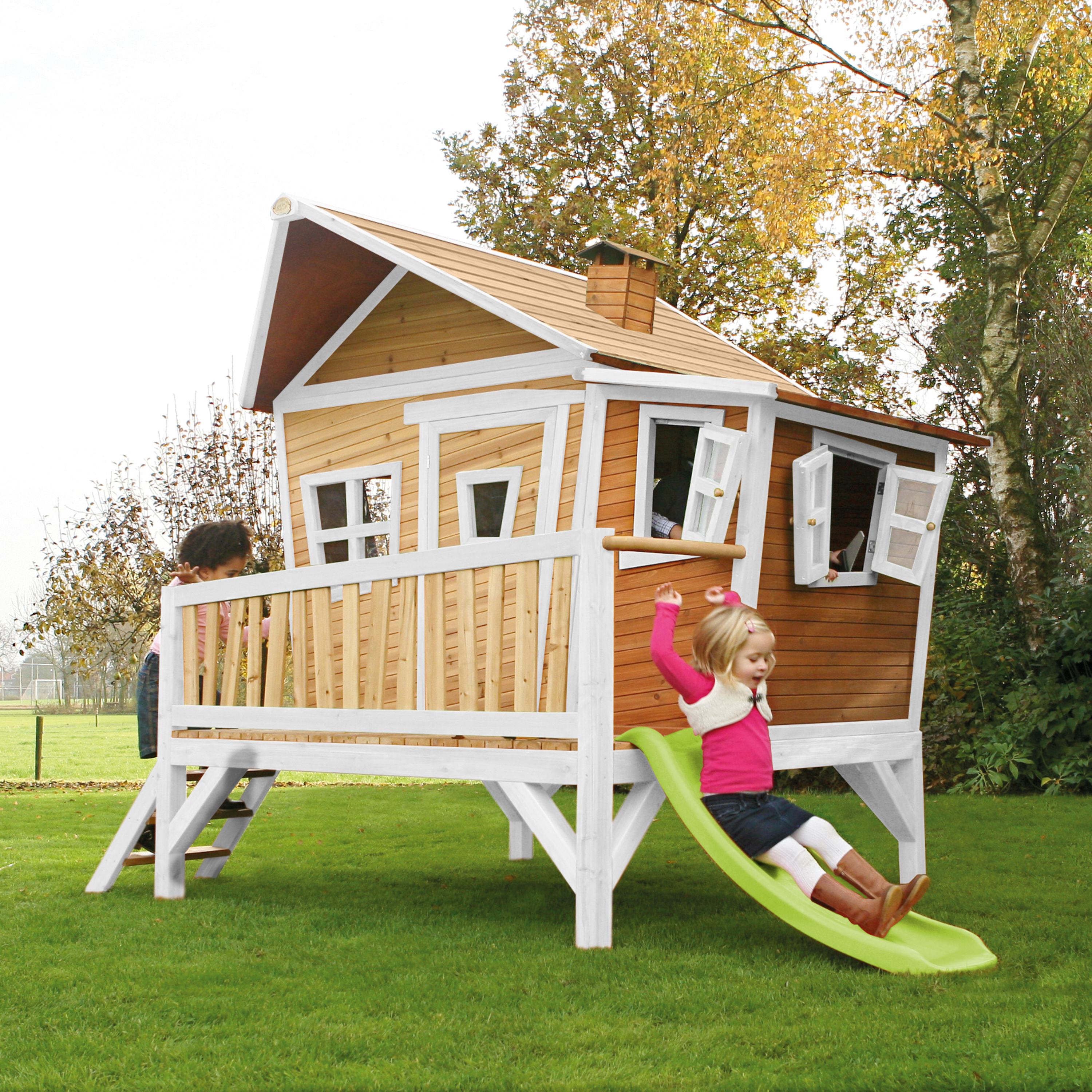 Kinder spielen auf einem Baumhaus mit Rutsche im Garten.