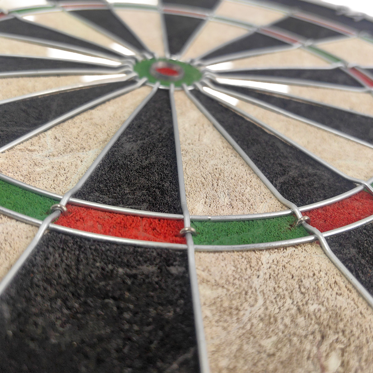 Nahaufnahme eines Dartboards mit schwarzen, hellbraunen und roten Segmenten.