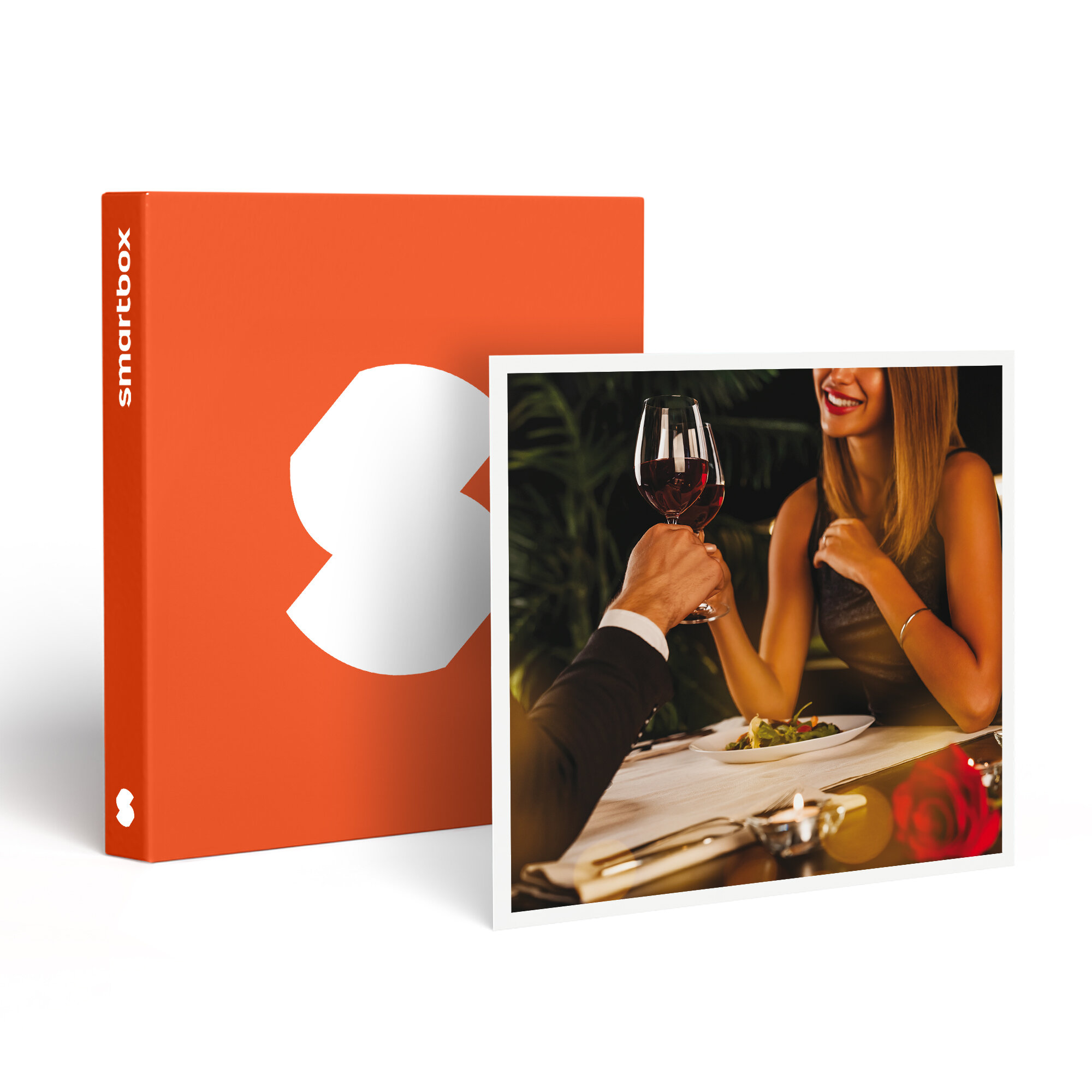 Una pareja choca copas de vino junto a una caja naranja con logo blanco.