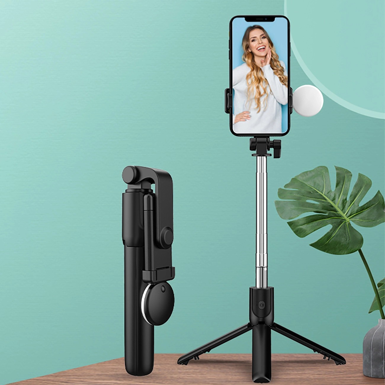 Ein schwarzer Selfie-Stick mit ausgefahrenem Stativ und daran befestigtem Telefon mit Frau.