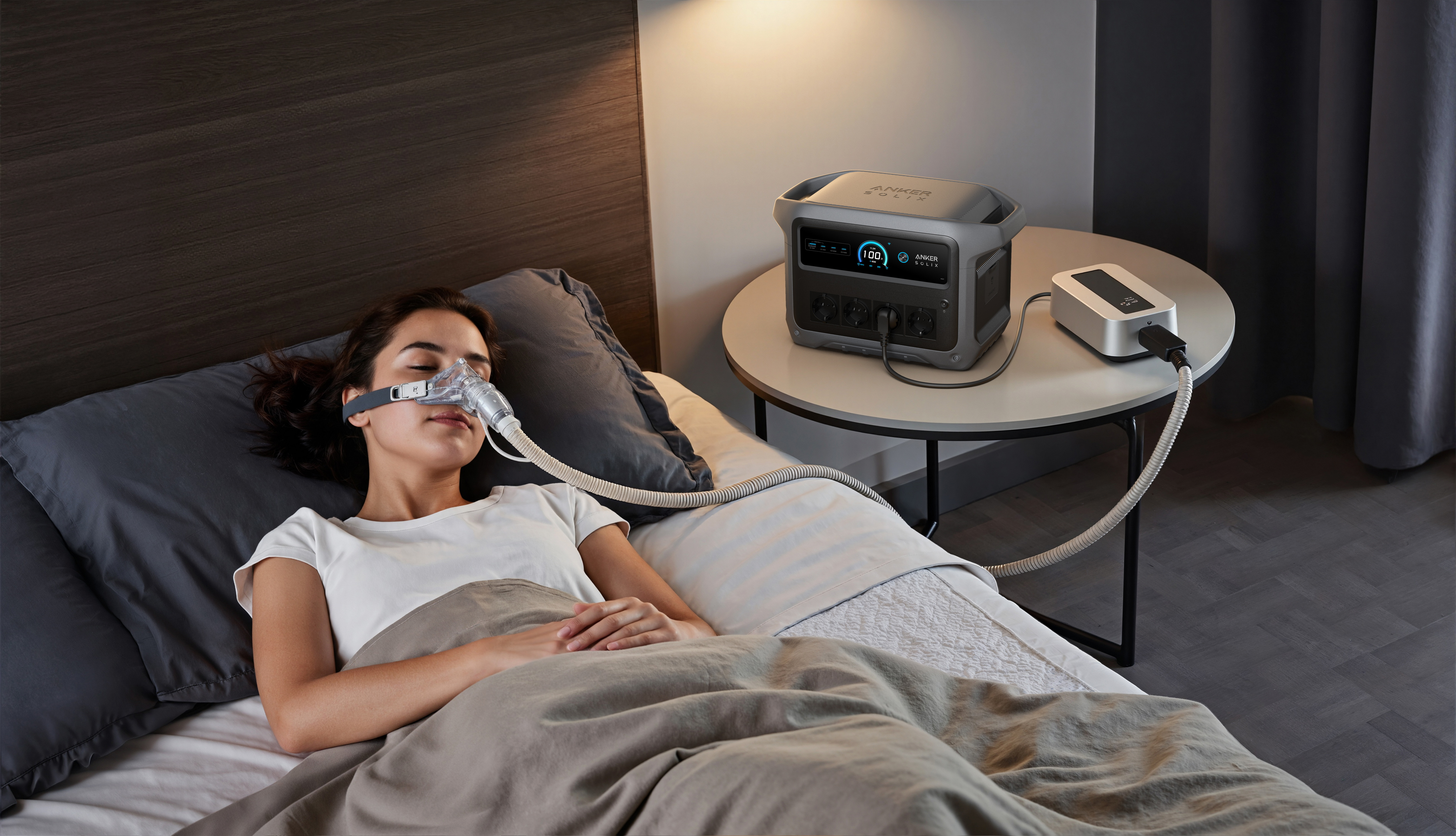 Kobieta w masce CPAP śpi w łóżku obok urządzenia Anker Solix.