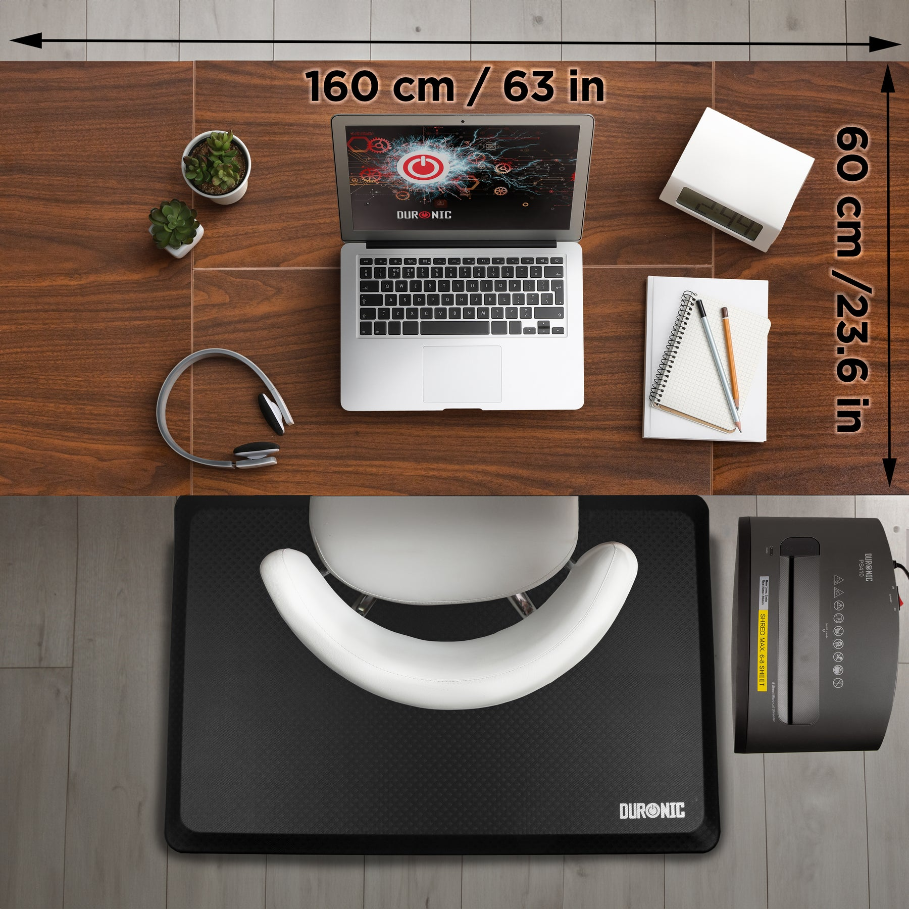 Büro-Setup mit Laptop, Kopfhörern, Pflanzen, Uhr, Notizbuch und Aktenvernichter.