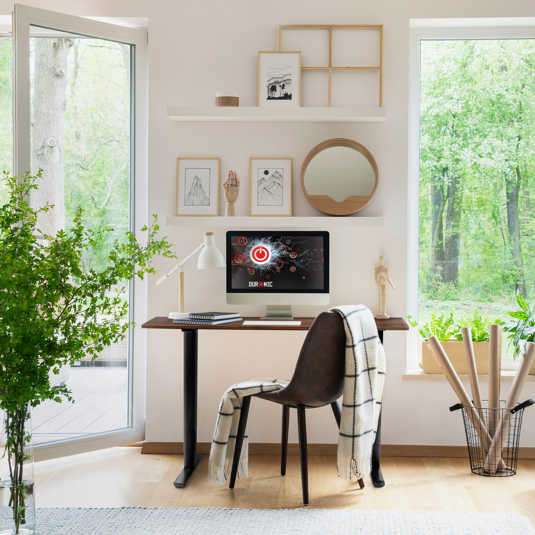 Ein Schreibtisch mit Computer, Stuhl, Lampe und Pflanzen vor einem Fenster.