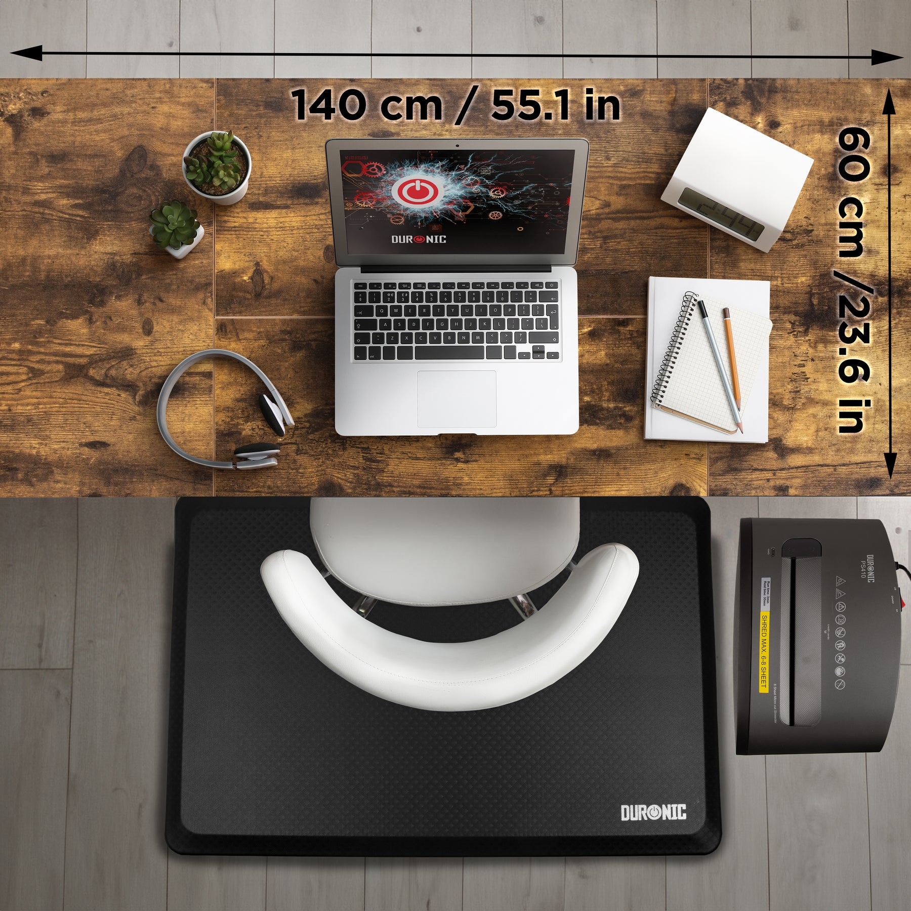 Schreibtisch mit Laptop, Kopfhörern, Pflanzen, Uhr, Notizbuch und Aktenvernichter.