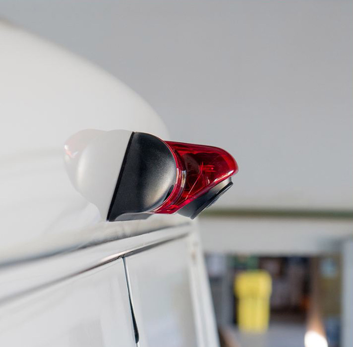 Ein rotes Rücklicht mit weißem und schwarzem Gehäuse auf einem weißen Fahrzeug.