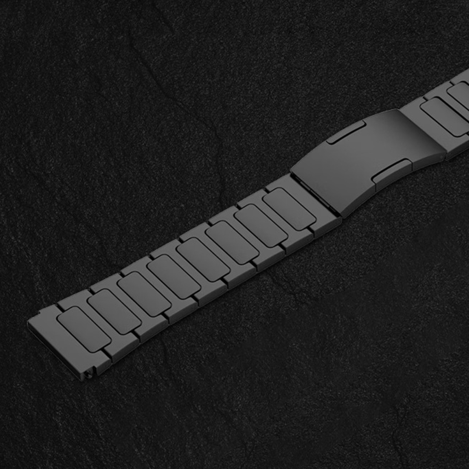 Ein graues Metallarmband mit Gliedern auf schwarzem Hintergrund.