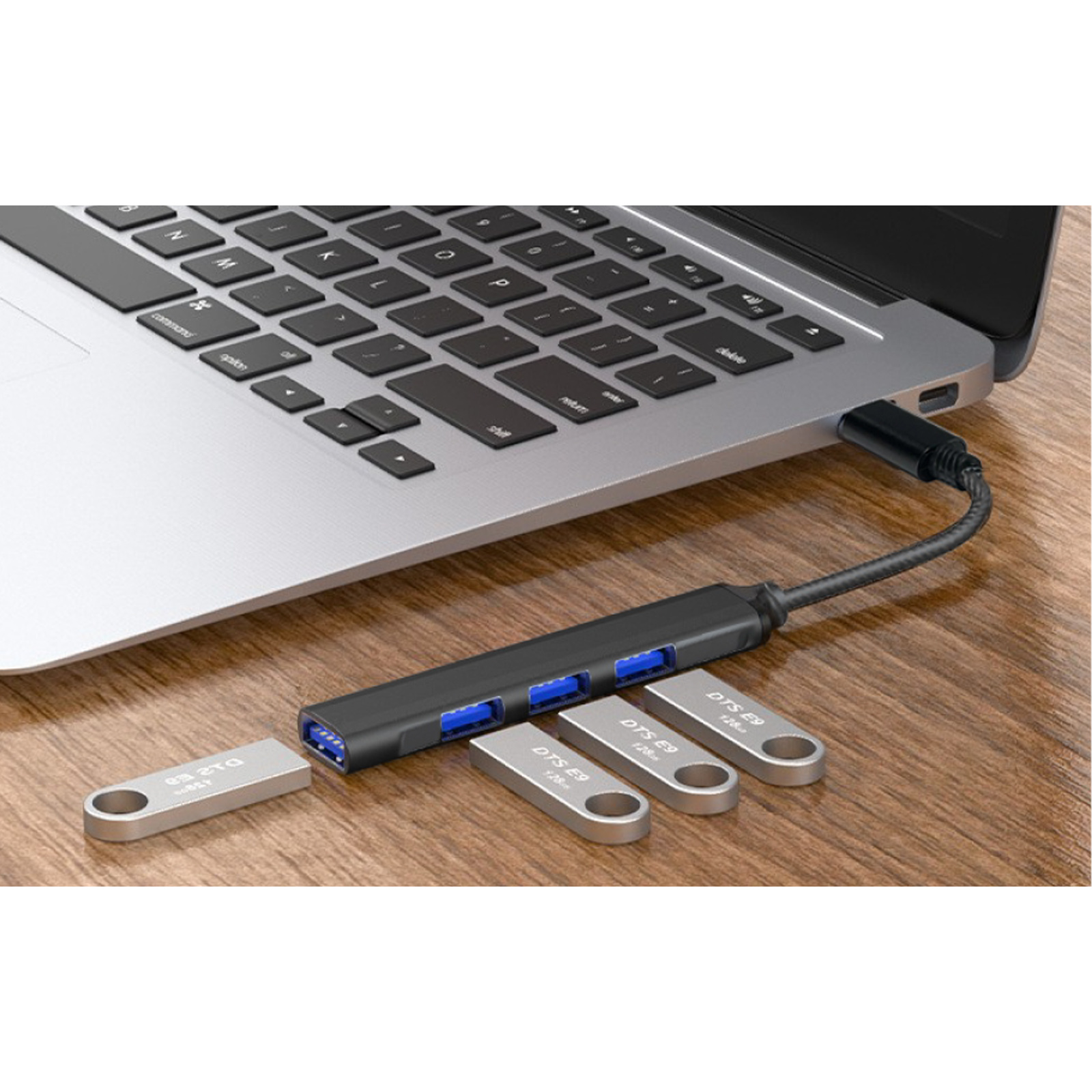 Un concentrador USB negro está conectado a un portátil. Varios lápices de memoria están al lado.