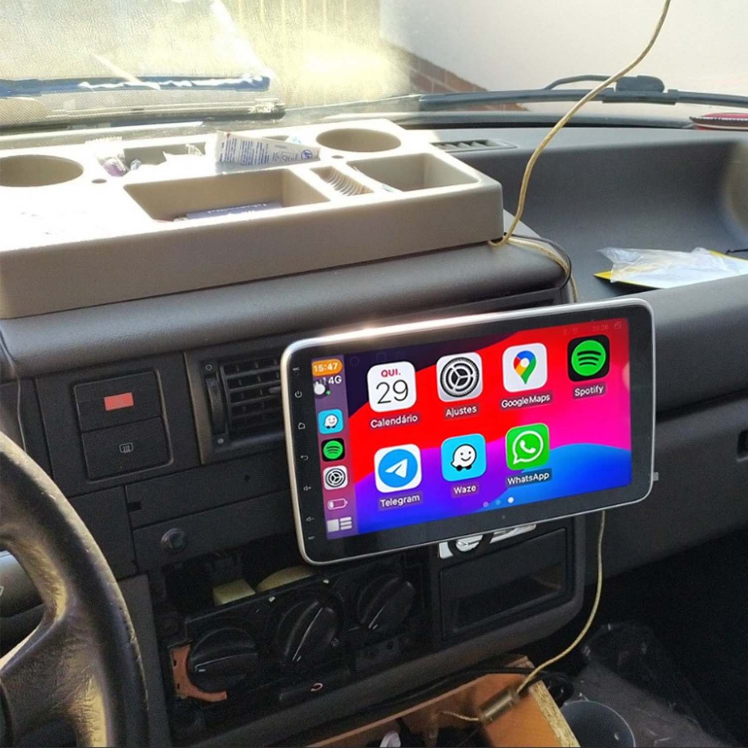 Cruscotto dell'auto con ampio touchscreen che mostra app del telefono come Calendario, Mappe, Spotify, WhatsApp.