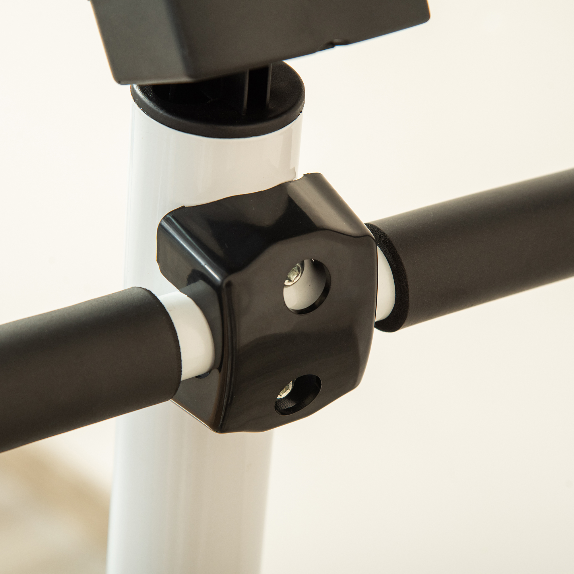 Zbliżenie czarnego uchwytu ze śrubami na białej rurze i czarnych uchwytach.