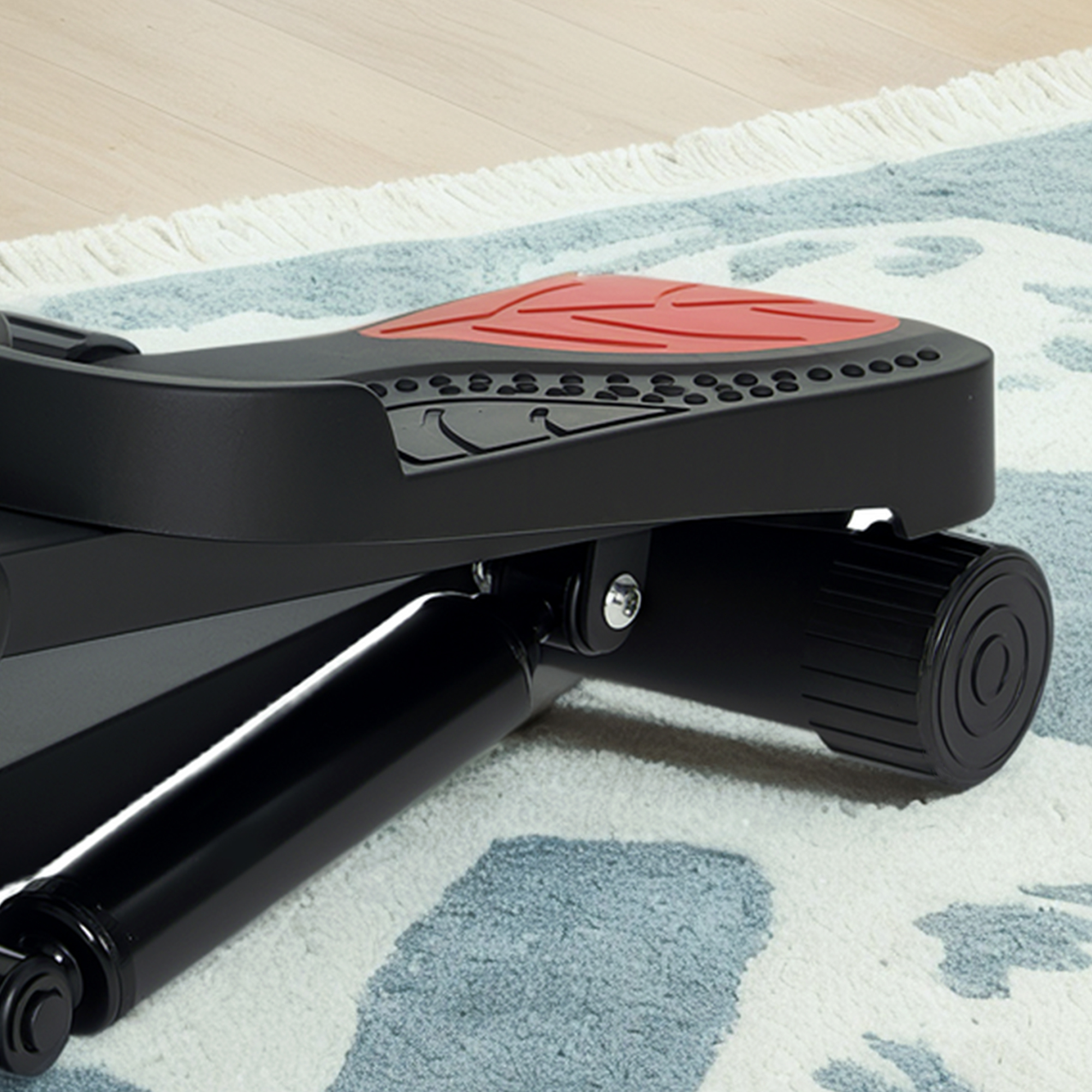 Czarny stepper z czerwoną bieżnią stoi na dywanie.