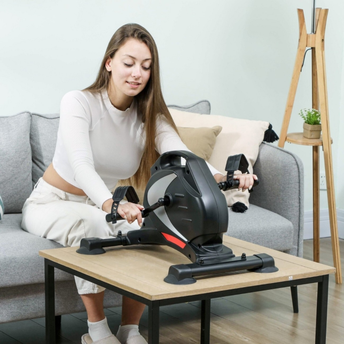 Kobieta na kanapie używa czarnego roweru treningowego.