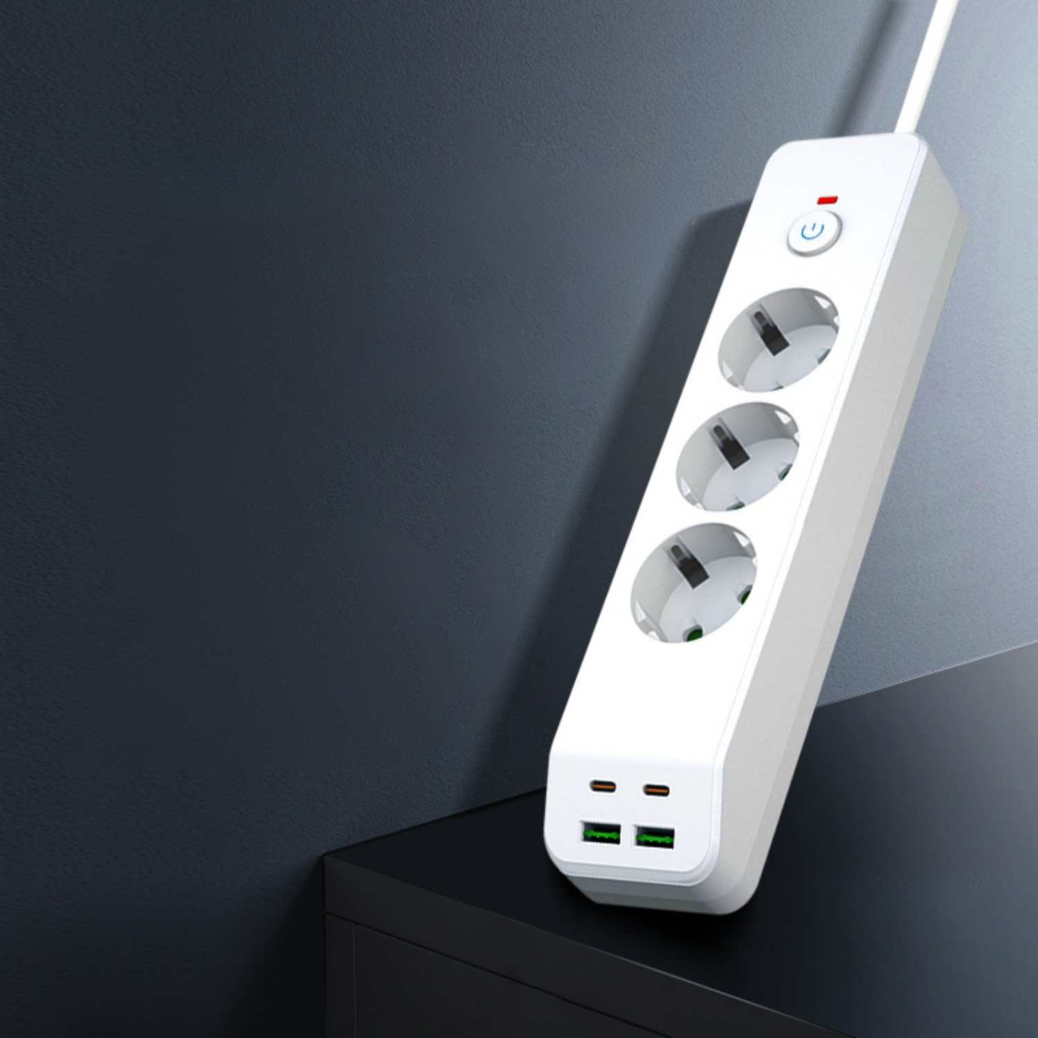 Weiße Steckdosenleiste mit drei Steckplätzen und zwei USB-Anschlüssen auf schwarzem Tisch.