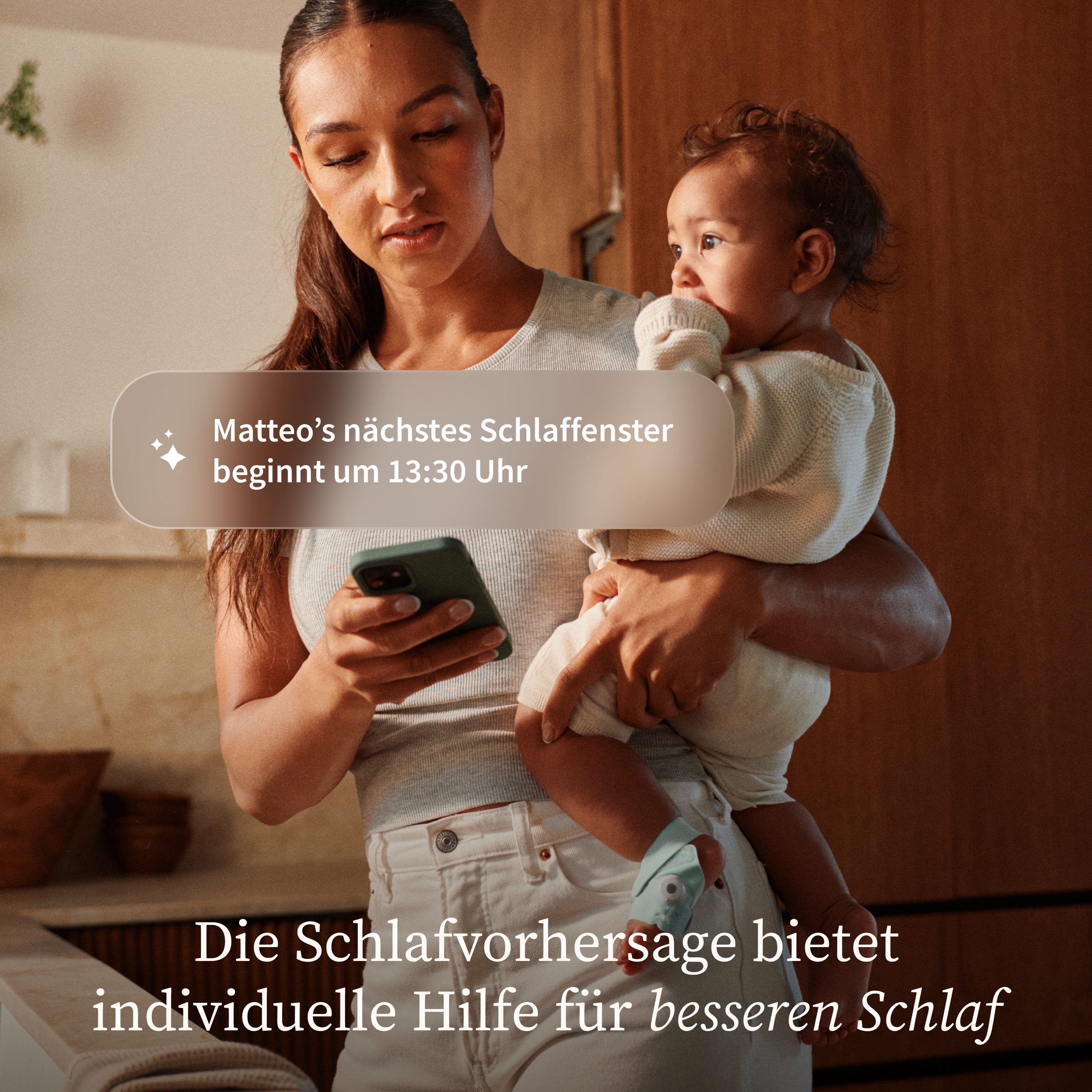 Eine Frau hält ein Baby und schaut auf ihr Handy. Eine Nachricht zeigt Matteo's Schlaffenster.