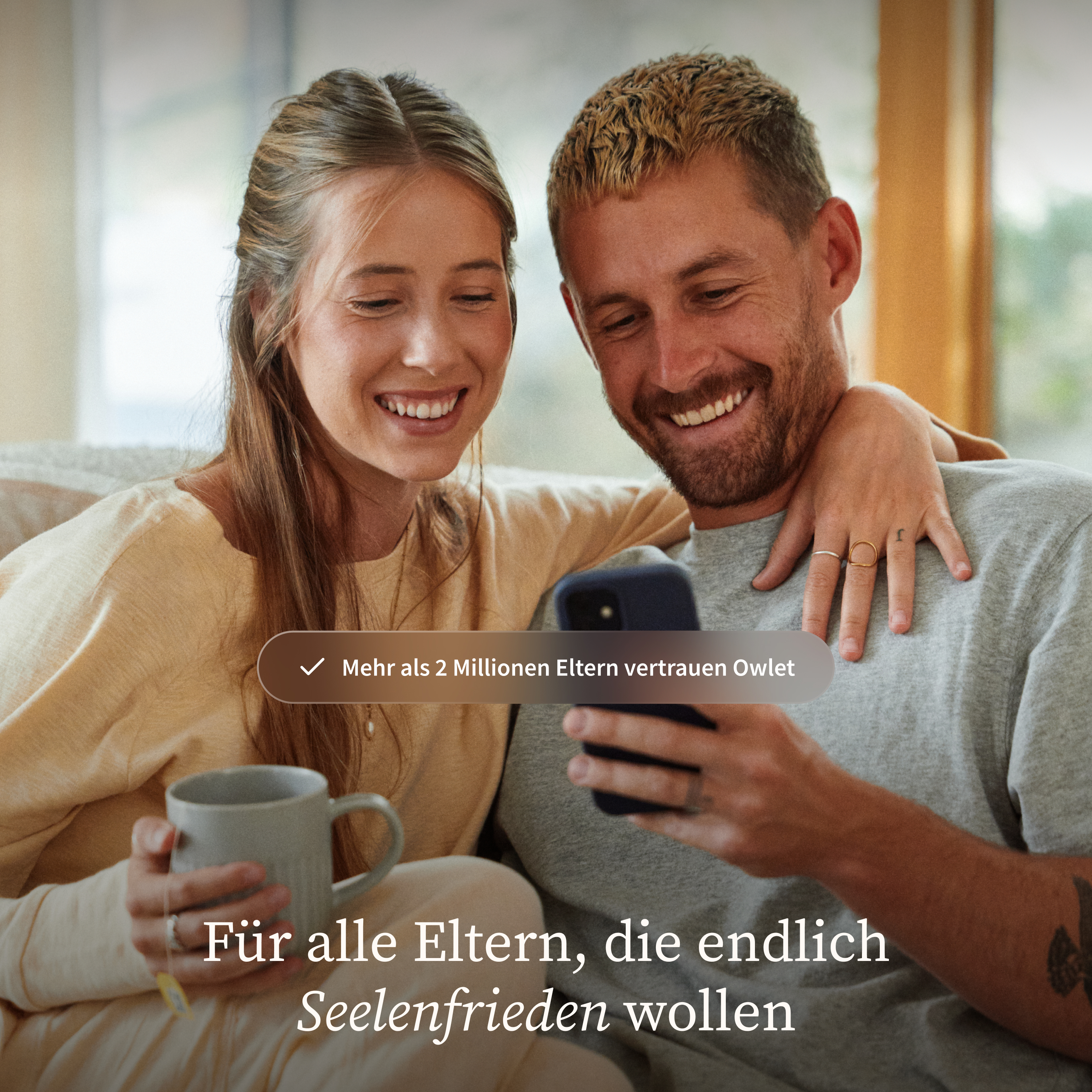 Ein Paar lacht und schaut auf ein Handy. "Mehr als 2 Mio. Eltern vertrauen Owlet."