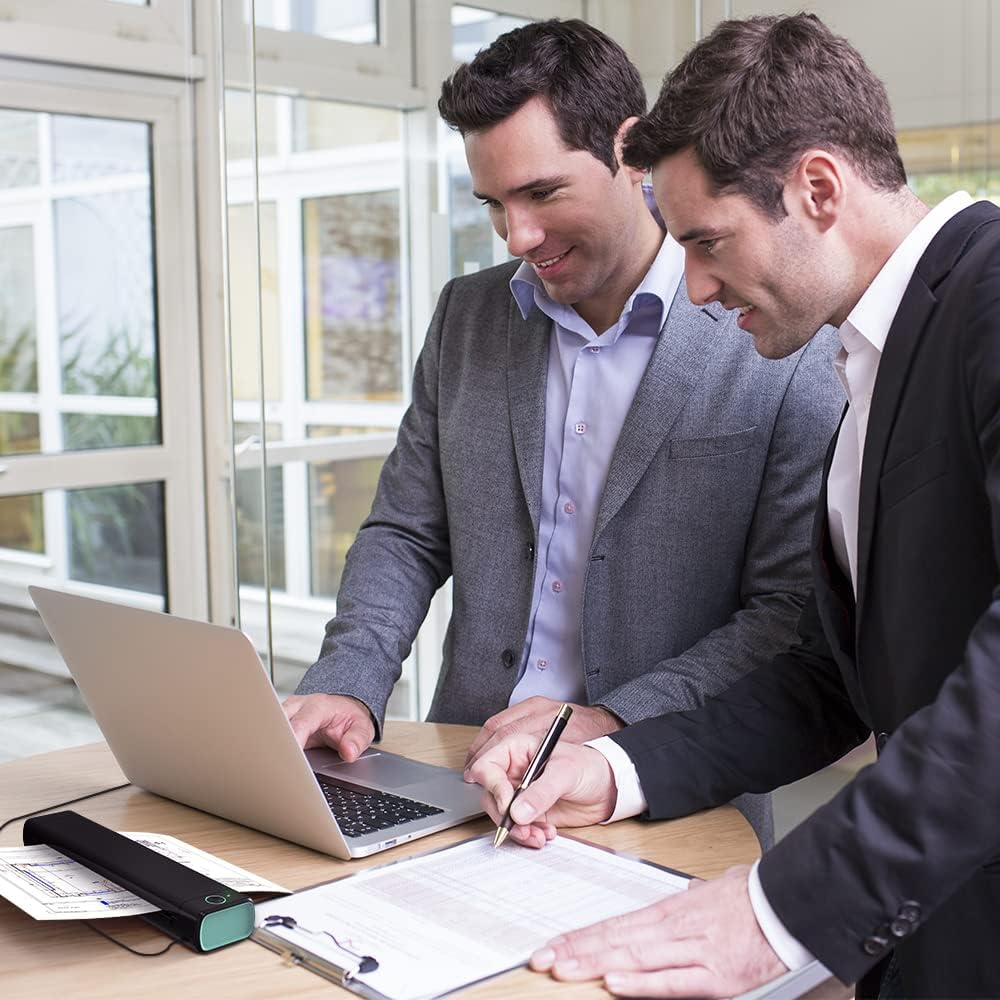 Deux hommes en costume travaillent sur un ordinateur portable et signent des documents.