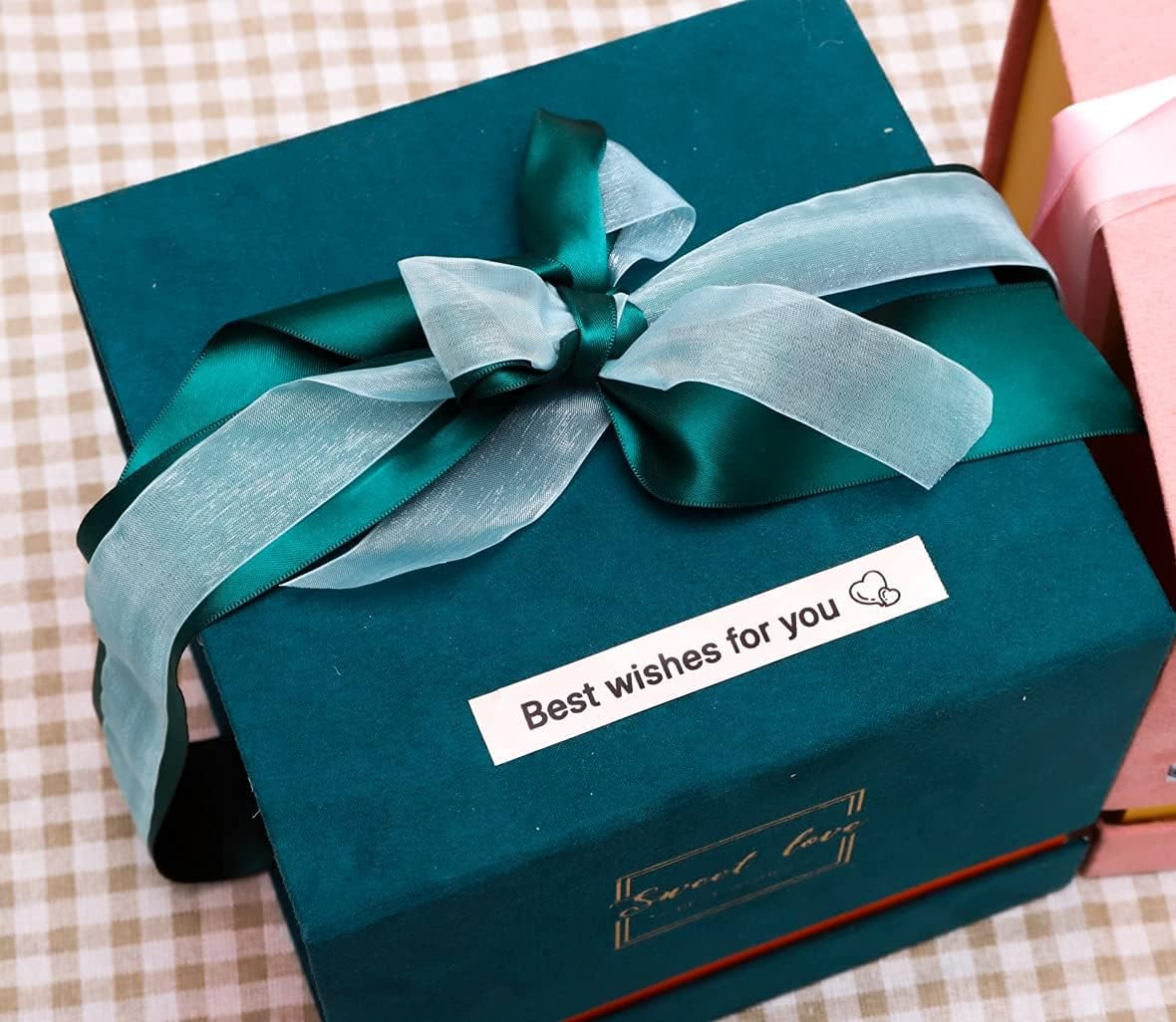 Boîte cadeau vert foncé avec un nœud et une carte "Meilleurs vœux pour vous".