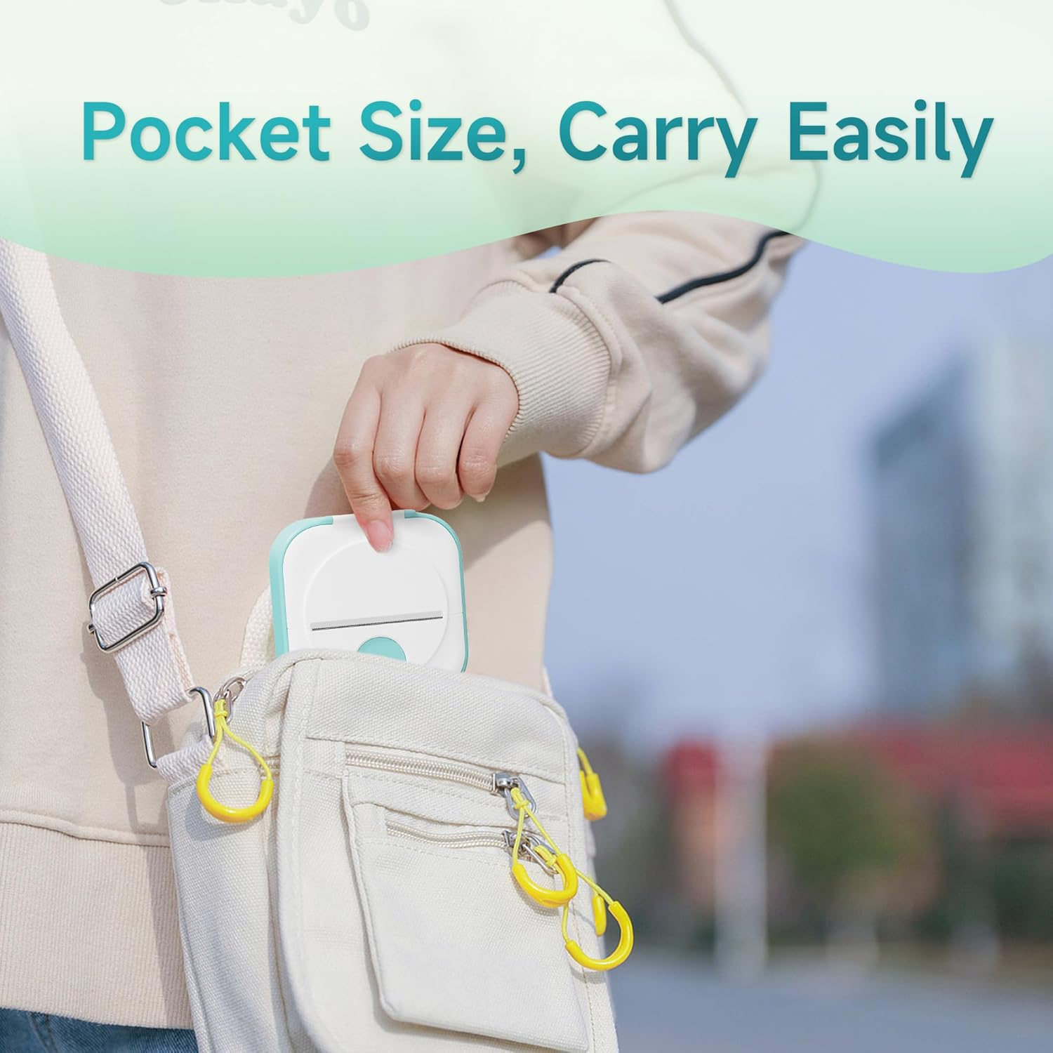 Une main place une petite imprimante blanche dans un sac bandoulière beige. Le texte dit 'Pocket Size, Carry Easily'.