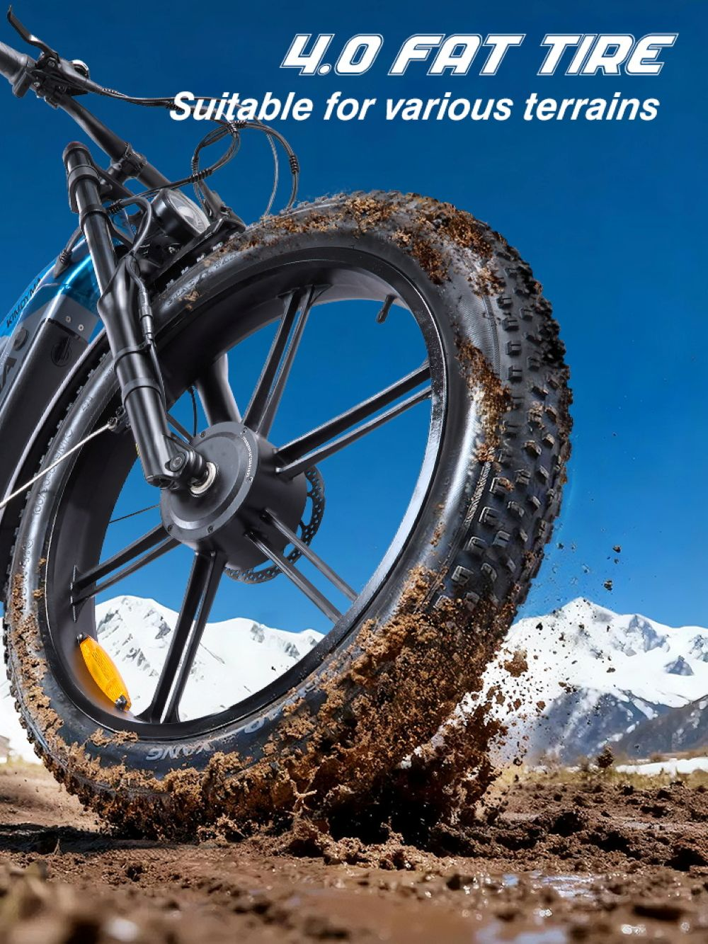 Una e-bike con pneumatici grassi attraversa terreno fangoso, montagne innevate sullo sfondo.