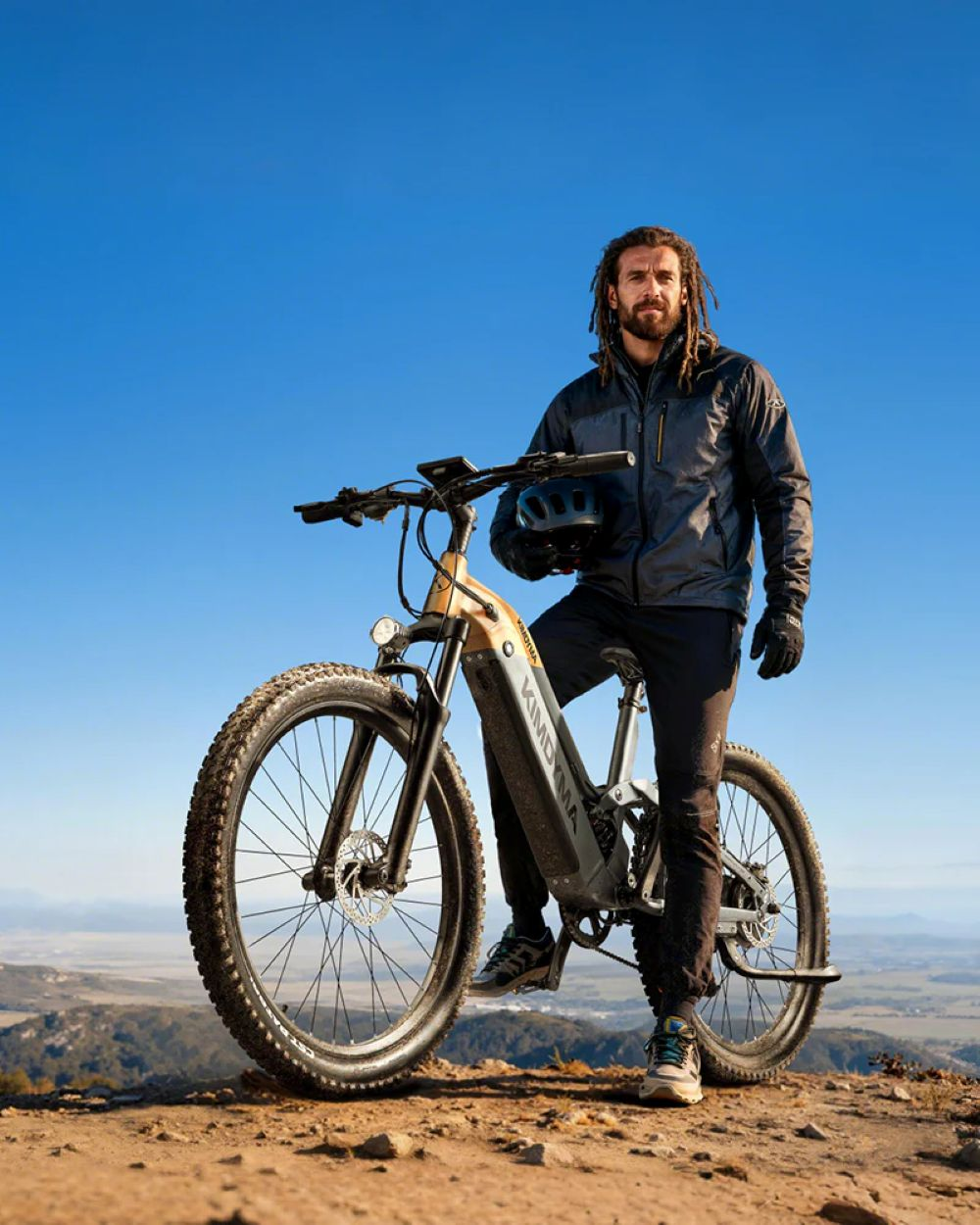 Uomo con dreadlocks accanto a una e-bike su una collina.