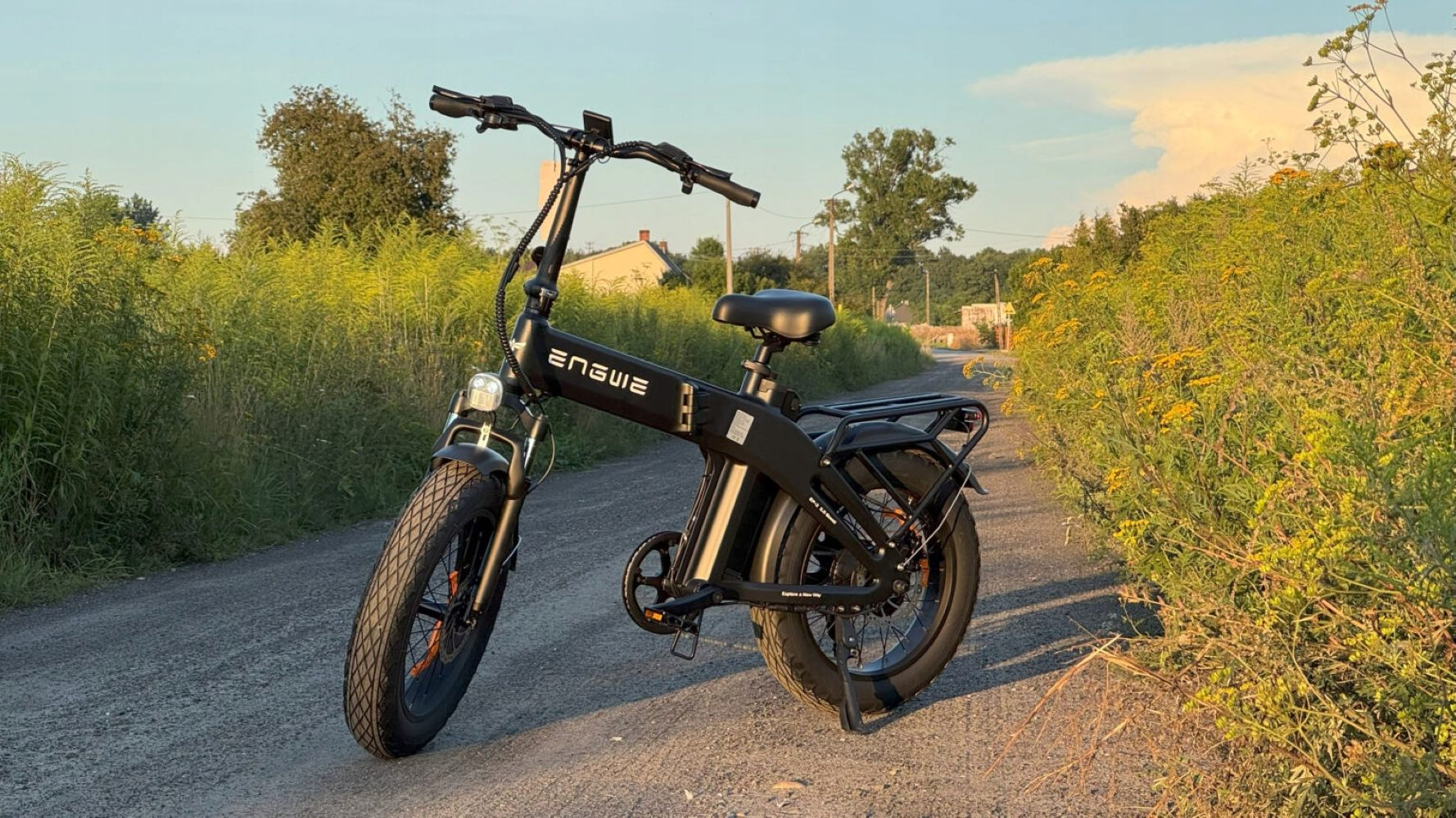 Una e-bike nera parcheggiata su una strada sterrata accanto a lussureggiante vegetazione.
