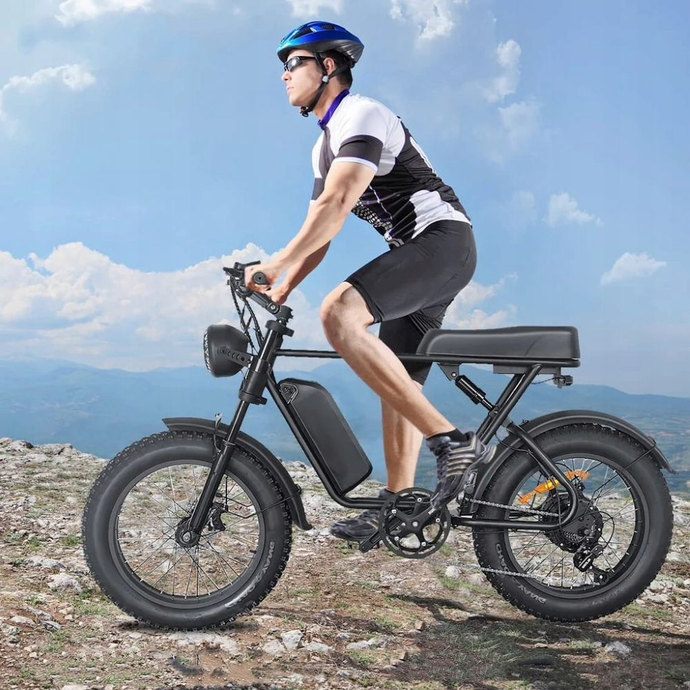 Un uomo guida una e-bike nera su terreno roccioso sotto un cielo blu.